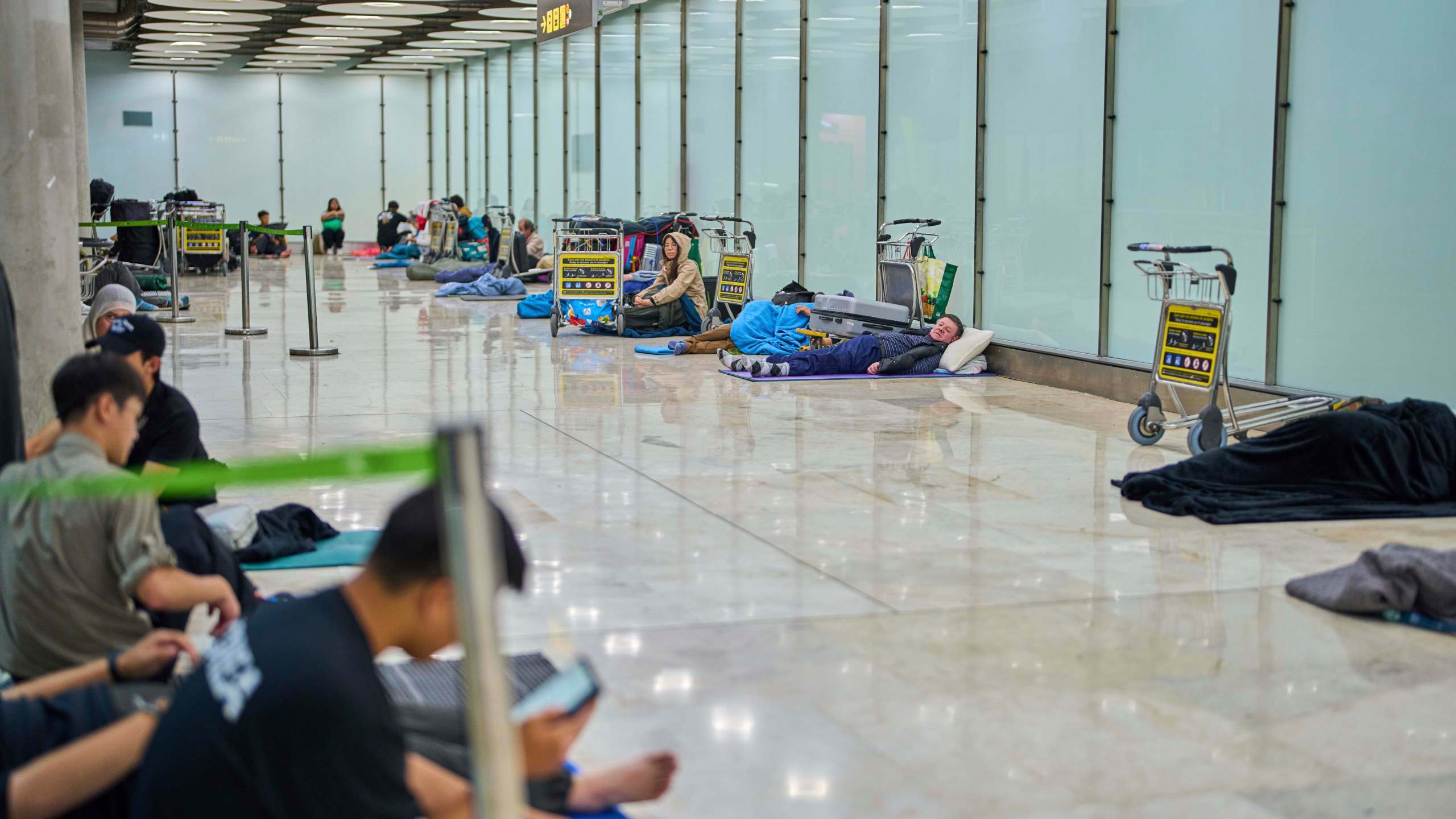 People sleep on the floor of Terminal 4 at Adolfo Suarez-Madrid Barajas Airport in Madrid, Spain, Thursday, May 15, 2025. (AP Photo/Manu Fernandez)