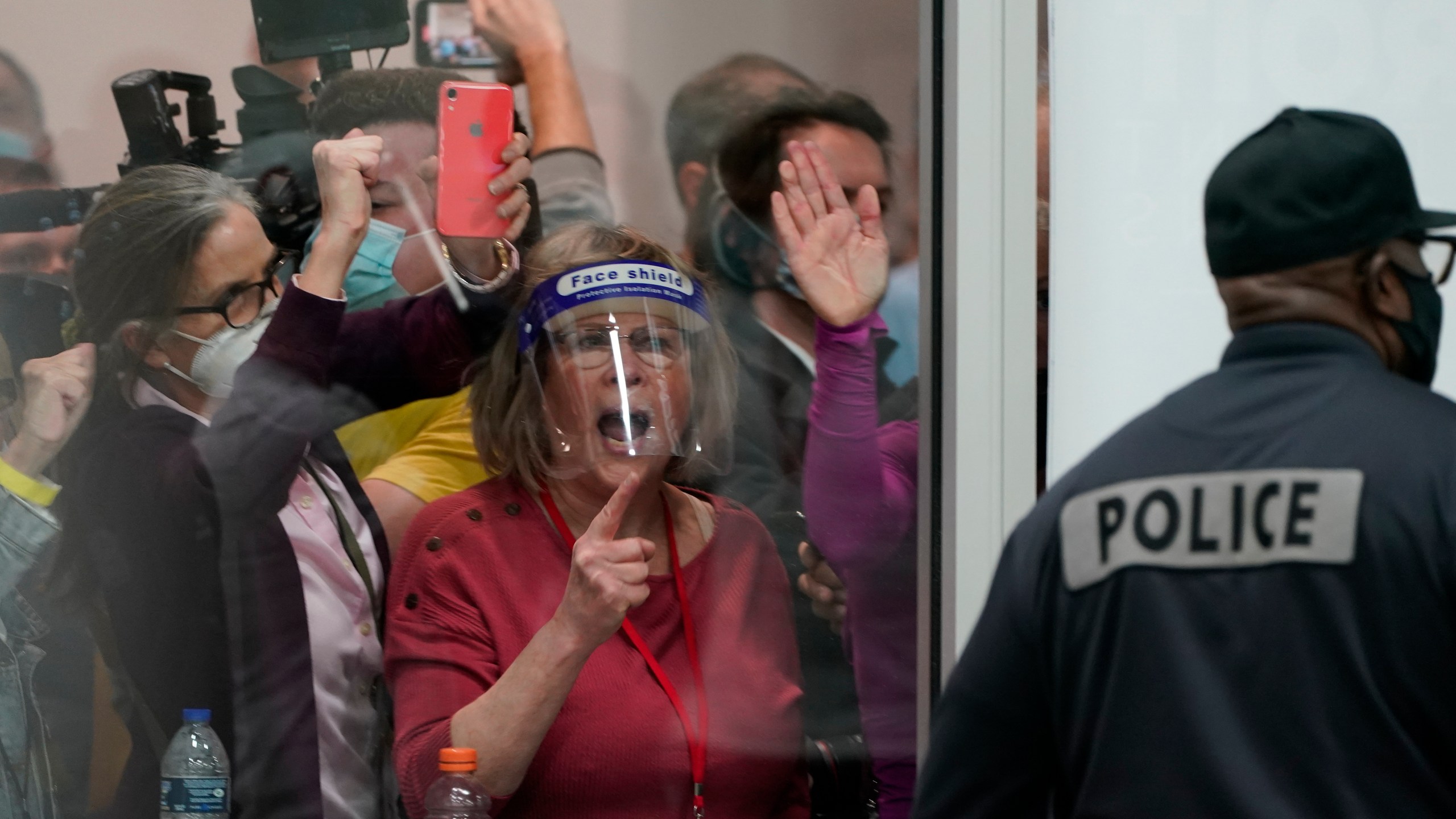 FILE - Election challengers yell as they look through the windows of the central counting board as police were helping to keep additional challengers from entering due to overcrowding, Nov. 4, 2020, in Detroit. (AP Photo/Carlos Osorio, File)