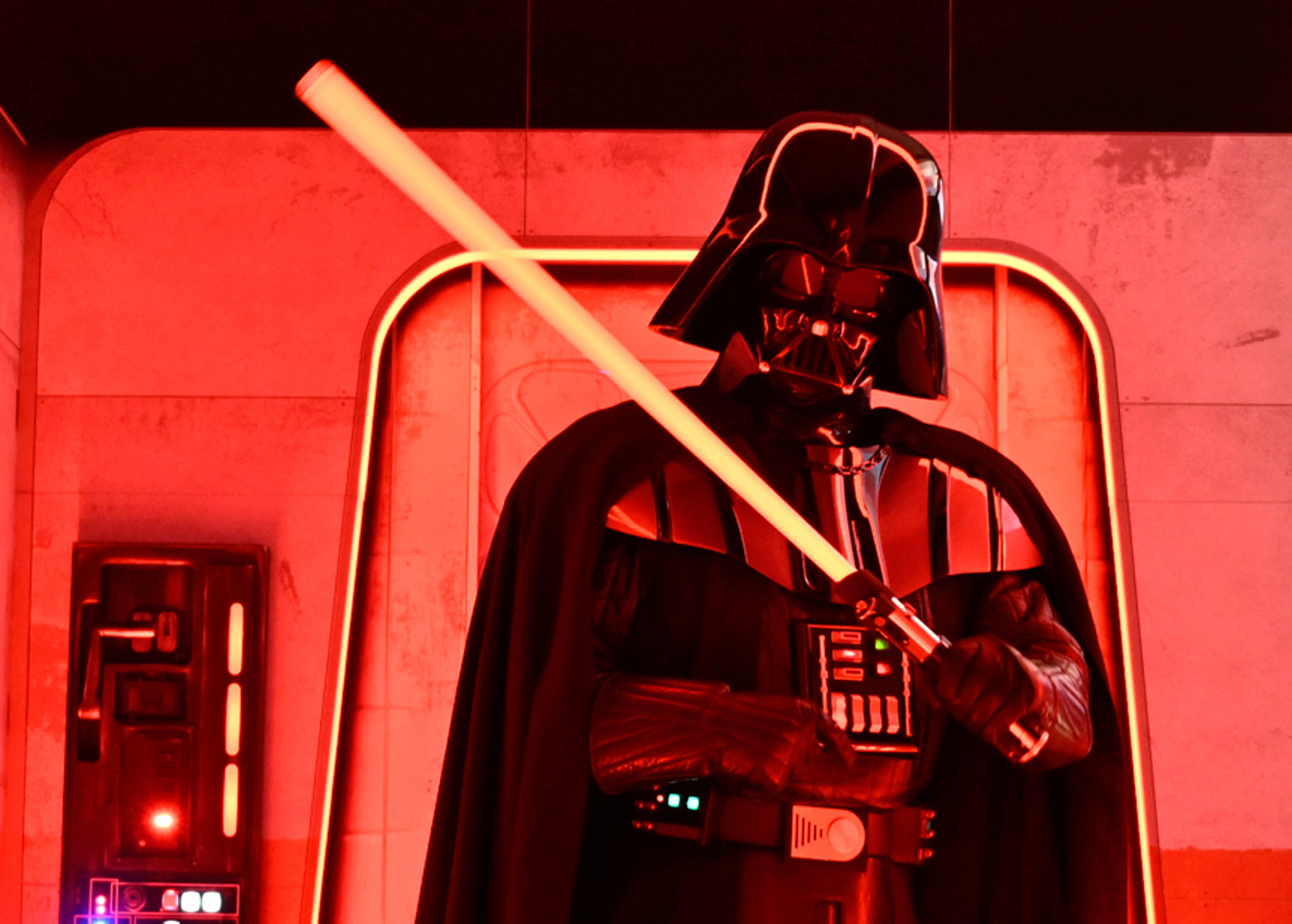 A Darth Vader costumed character poses with a lightsaber