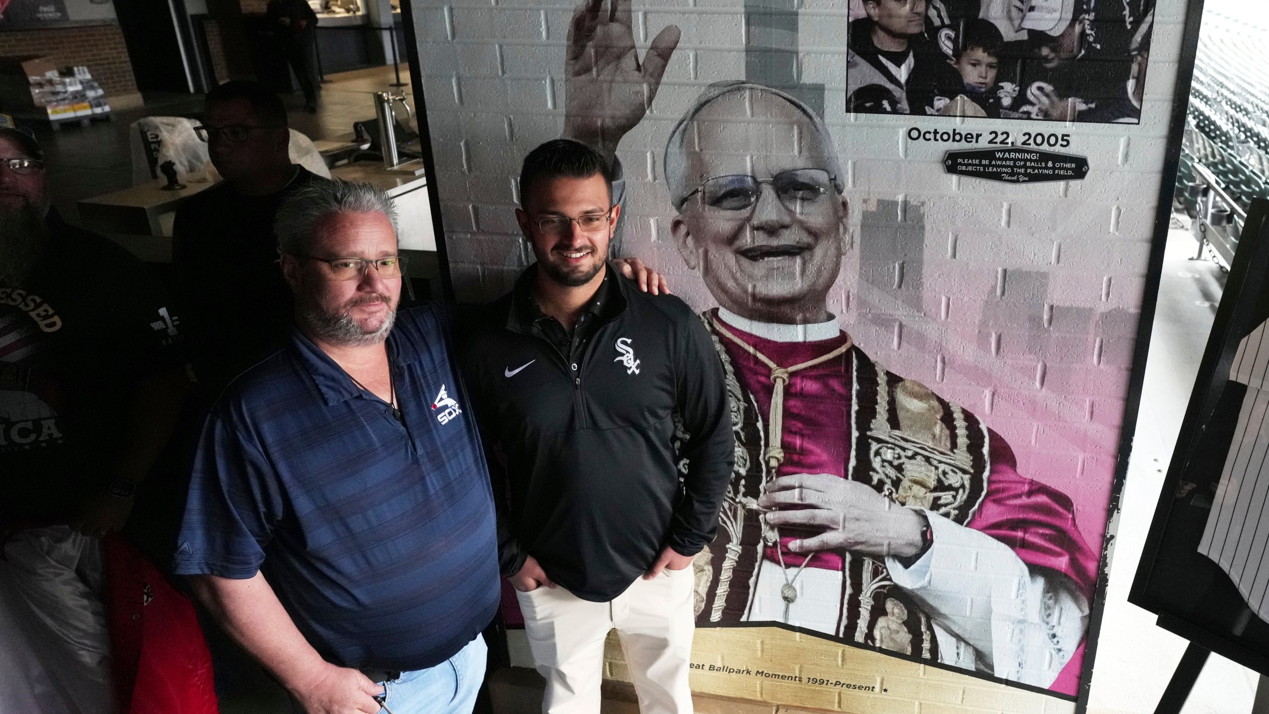 Eddie Schmit III, left, and his son Eddie Schmit IV, right, pose for a photo after a news conference for the Chicago White Sox's commemoration of team fan Pope Leo XIV with a graphic installation at Rate Field before a baseball game between the Seattle Mariners and the White Sox in Chicago, Monday, May 19, 2025. (AP Photo/Nam Y. Huh)