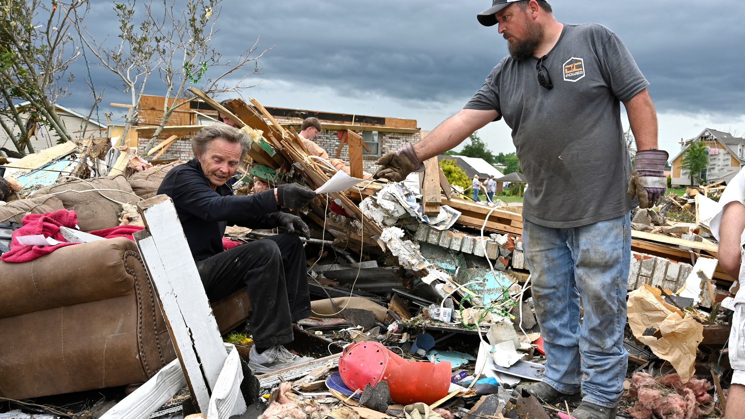 Donovan Queen, right, hands Dam Barnett some photographs that he dug out of the remains of his home in the Sunshine Hills neighborhood in London, Ky., Monday, May 19, 2025. (AP Photo/Timothy D. Easley)