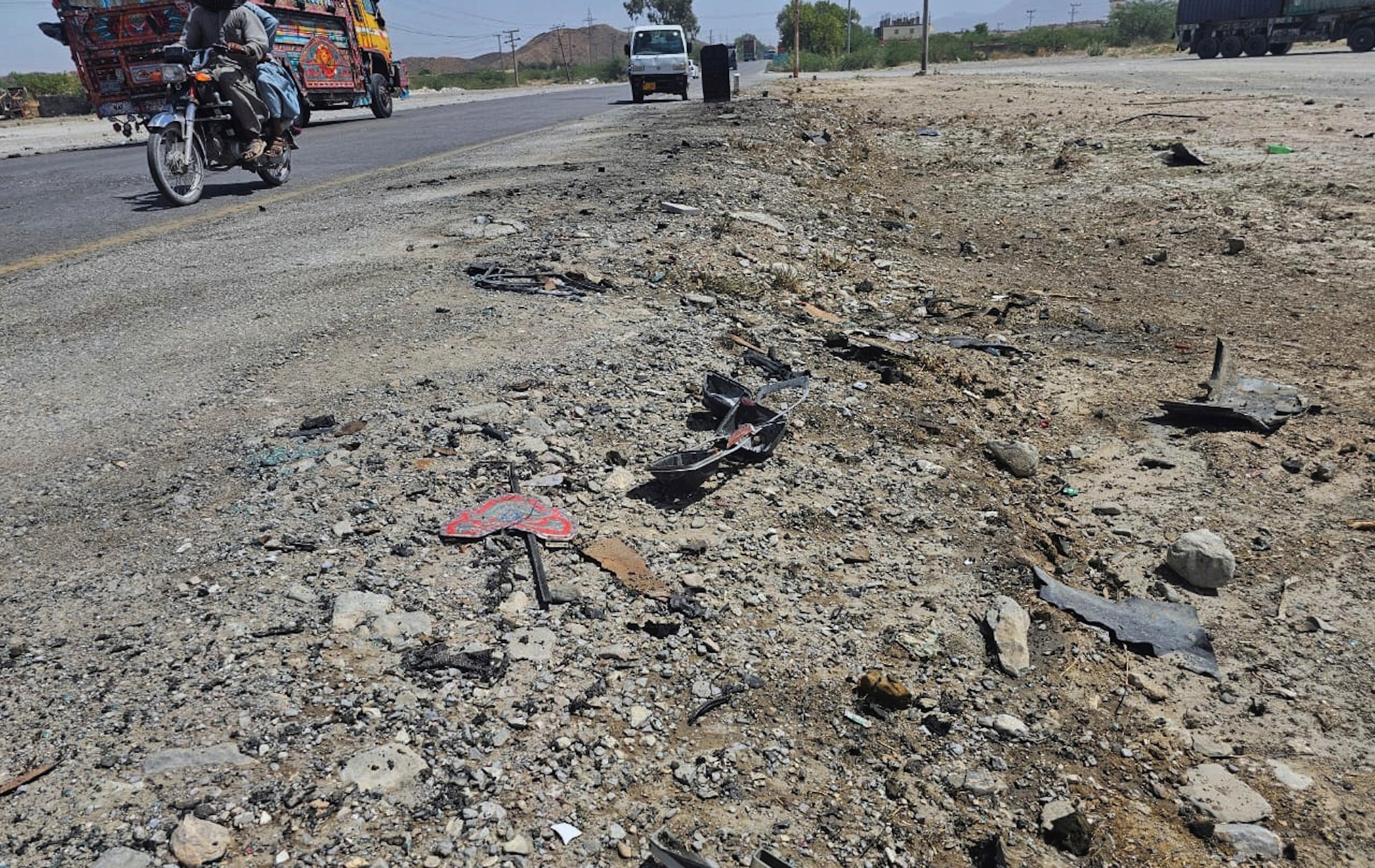 A motorcyclist and vehicles drive past the site of suicide bombing at a highway on the outskirts of the city of Khuzdar, in southwestern Pakistan, Wednesday, May 21, 2025. (AP Photo)