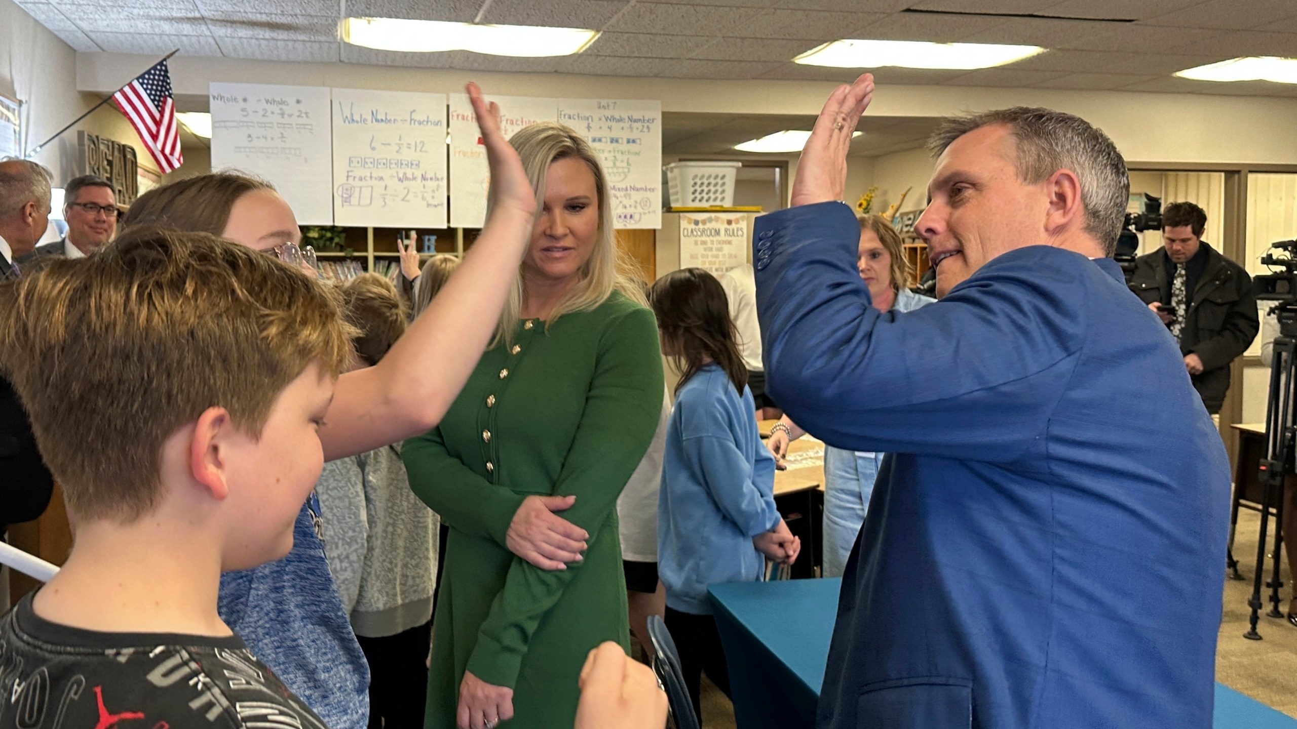 North Dakota Republican Gov. Kelly Armstrong, at right, high-fives a student at Centennial Elementary School in Bismarck, N.D., on Friday, April 25, 2025, after he signed a bill for a "bell-to-bell" cellphone ban for public school K-12 students. At middle is first lady Kjersti Armstrong. (AP Photo/Jack Dura)