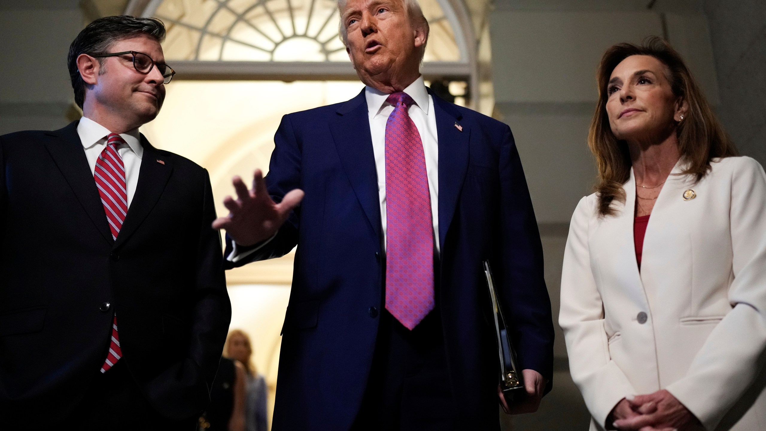 President Donald Trump, center, surrounded by Speaker of the House Mike Johnson, R-La., and Rep. Lisa McClain, R-Mich., speaks to reporters before a House Republican conference meeting, Tuesday, May 20, 2025, at the U.S. Capitol in Washington. (AP Photo/Julia Demaree Nikhinson)