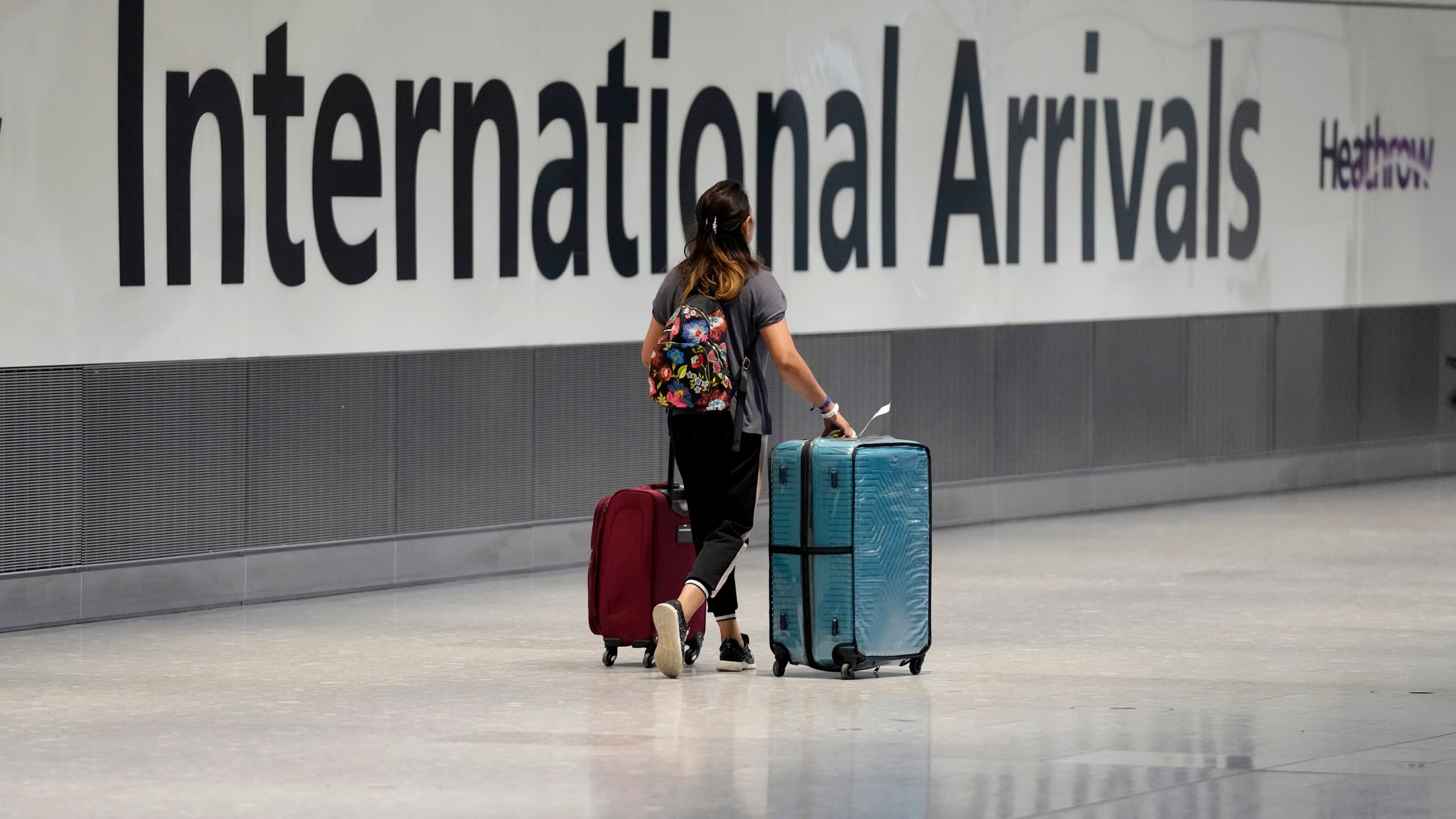A passenger carries luggage through an airport