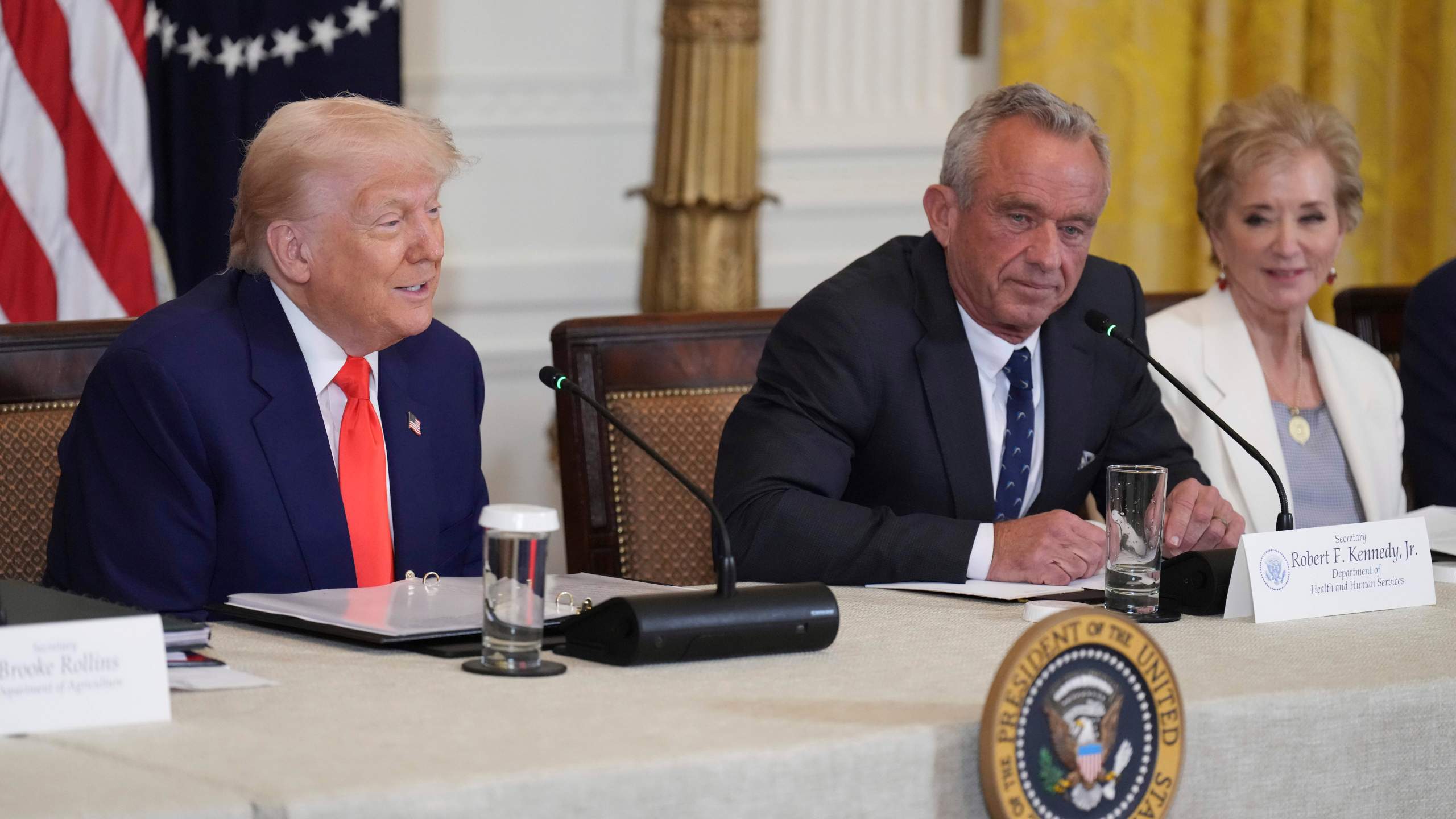 President Donald Trump, left, speaks as Education Secretary Linda McMahon, right, and Health and Human Services Secretary Robert F. Kennedy Jr. listen at a Make America Healthy Again (MAHA) Commission Event in the East Room of the White House, Thursday, May 22, 2025, in Washington. (AP Photo/Jacquelyn Martin)