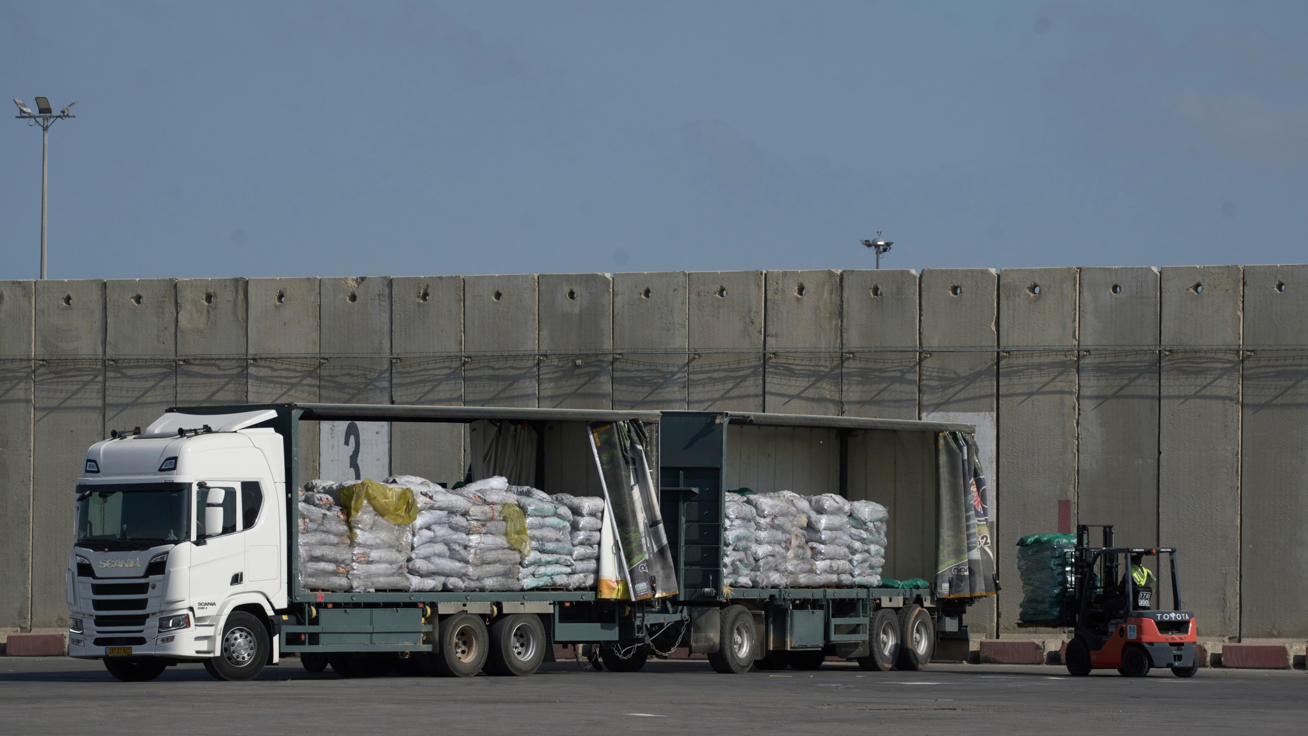 A worker unloads cargo from a truck carrying humanitarian aid for the Gaza Strip at the offload area of the Kerem Shalom border crossing between Israel and Gaza, southern Israel, Thursday, May 22, 2025. (AP Photo/Leo Correa)