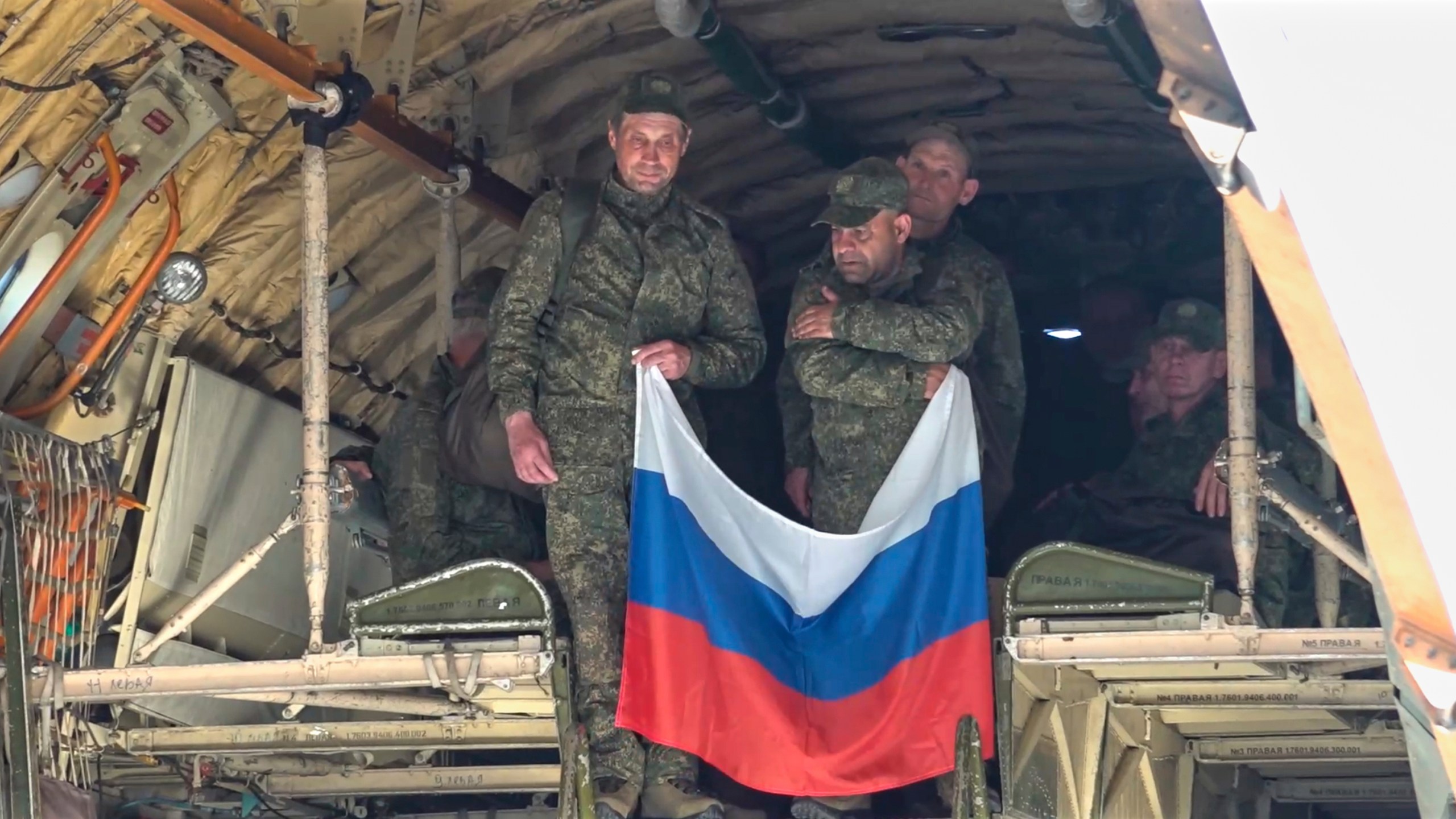 In this photo taken from video released by Russian Defense Ministry Press Service on Saturday, May 24, 2025, Russian servicemen hold a Russian flag upon arrival to Chkalovsky airport, outside Moscow, Russia, after returning from captivity by a POWs exchange between Russia and Ukraine. (Russian Defense Ministry Press Service photo via AP)