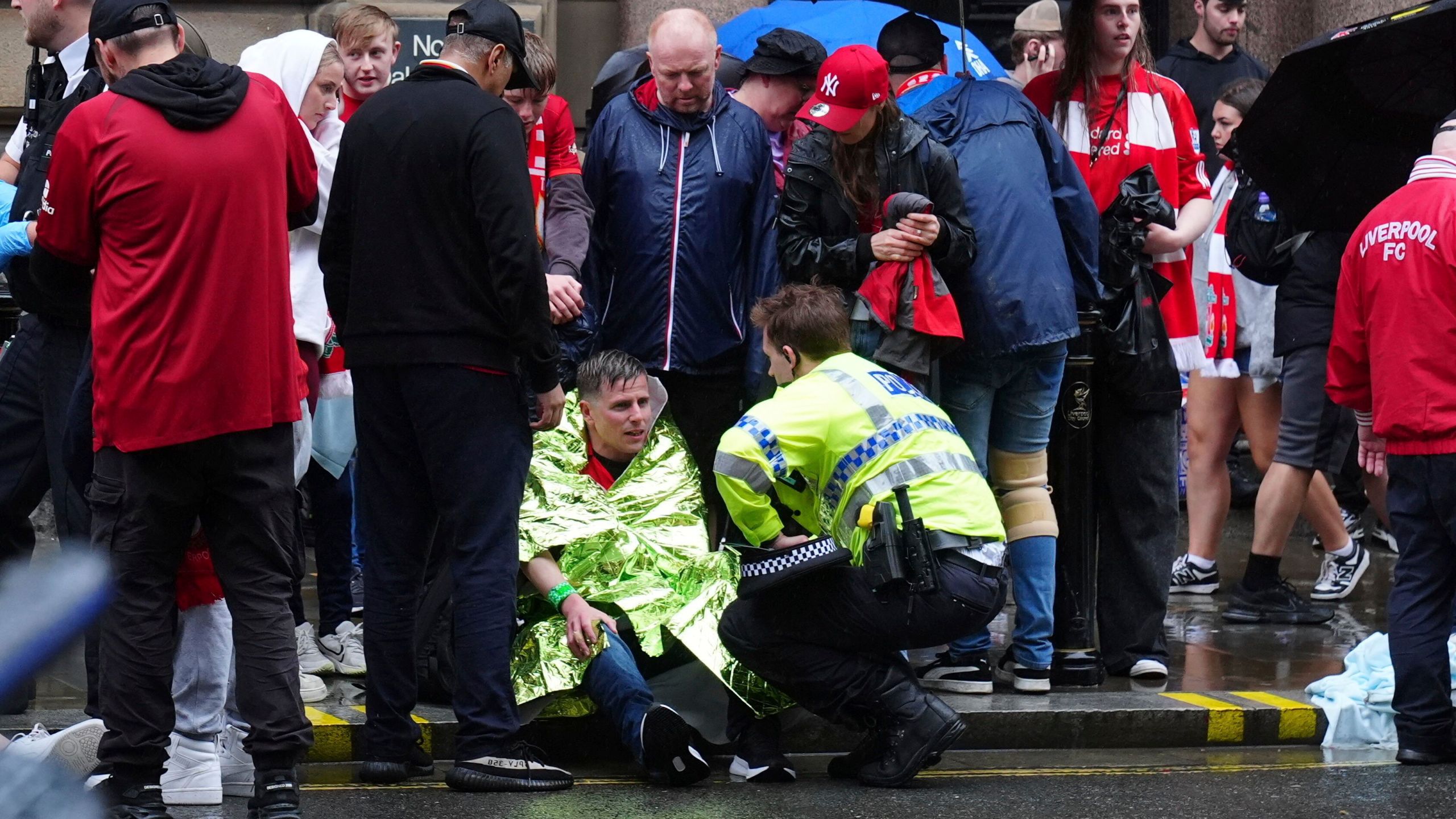 A police officer speaks with a man at the site of an incident on Water Street near the Liver Building in Liverpool after a car collided with pedestrians during the Premier League winners parade, in Liverpool, England, Monday May 26, 2025. (Owen Humphreys/PA via AP)