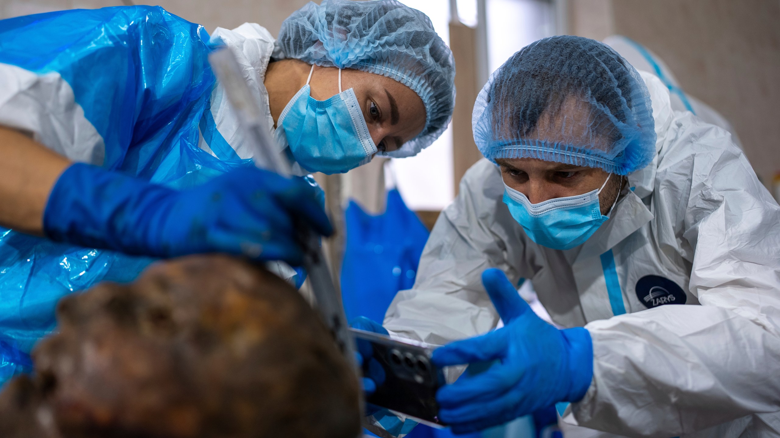 Forensic workers at a morgue in Kyiv, Ukraine, examine the body of a Ukrainian prisoner of war returned by Russia, June 24, 2024. (AP Photo/Alex Babenko)