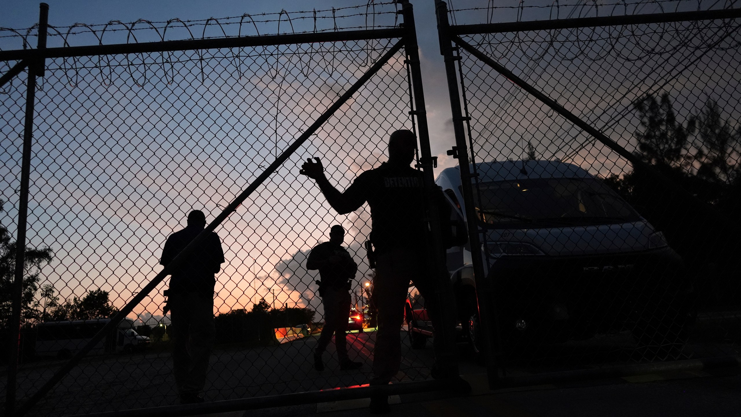 Krome Detention Center officers man an entrance gate as people hold a vigil outside to recognize those who have died in U.S. Immigration and Customs Enforcement custody, as well as those affected by mass deportations, Saturday, May 24, 2025, in Miami. (AP Photo/Rebecca Blackwell)