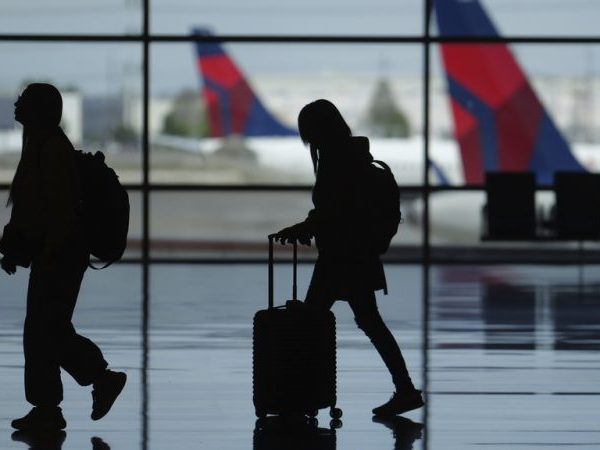 Travelers walk through airport holding luggage