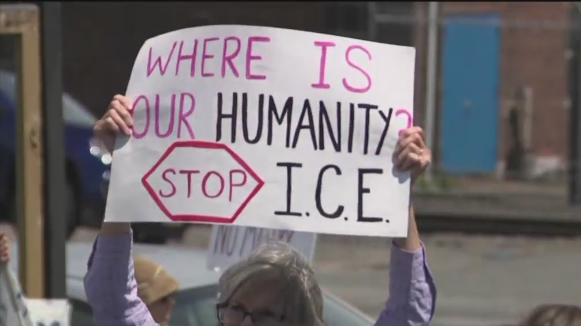 A protester holds a sign reading WHERE IS OUR HUMANITY STOP ICE