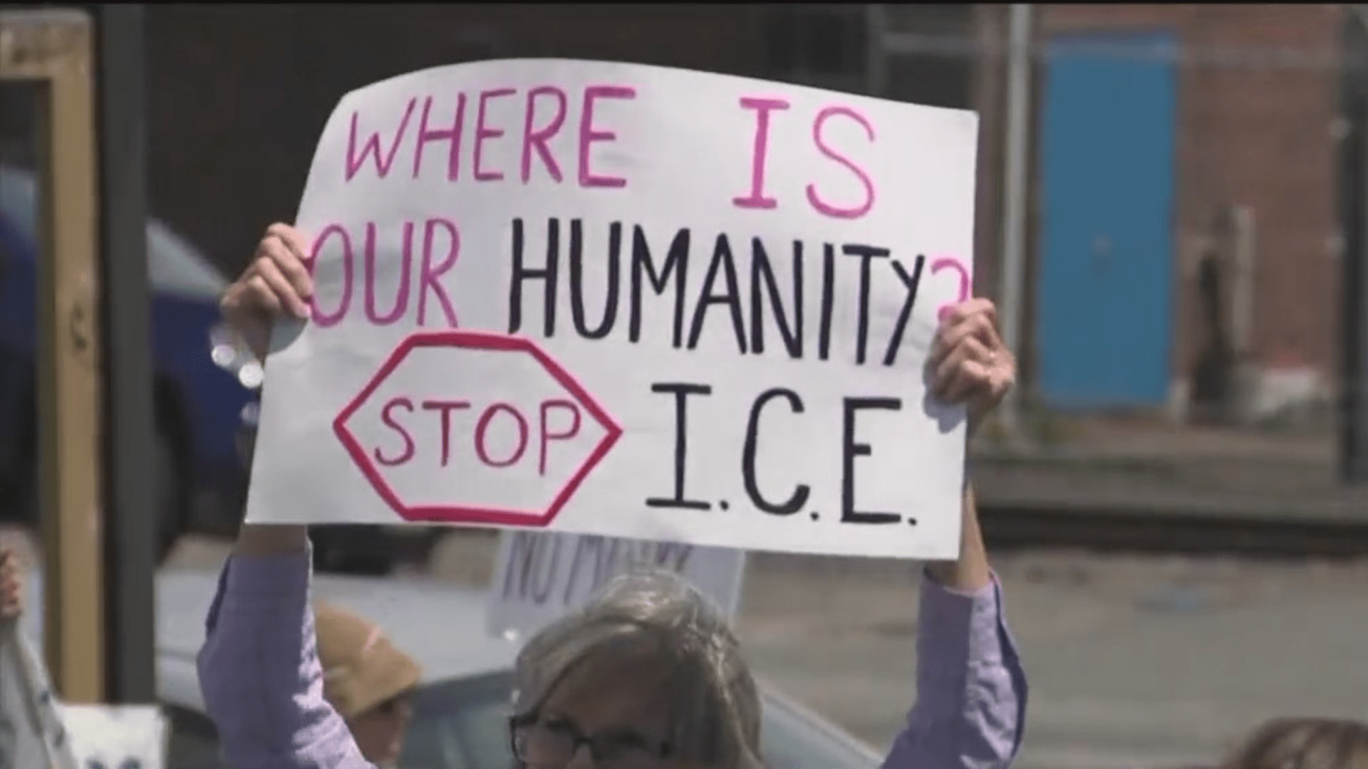 someone holds up a sign reading WHERE IS OUR HUMANITY; STOP ICE