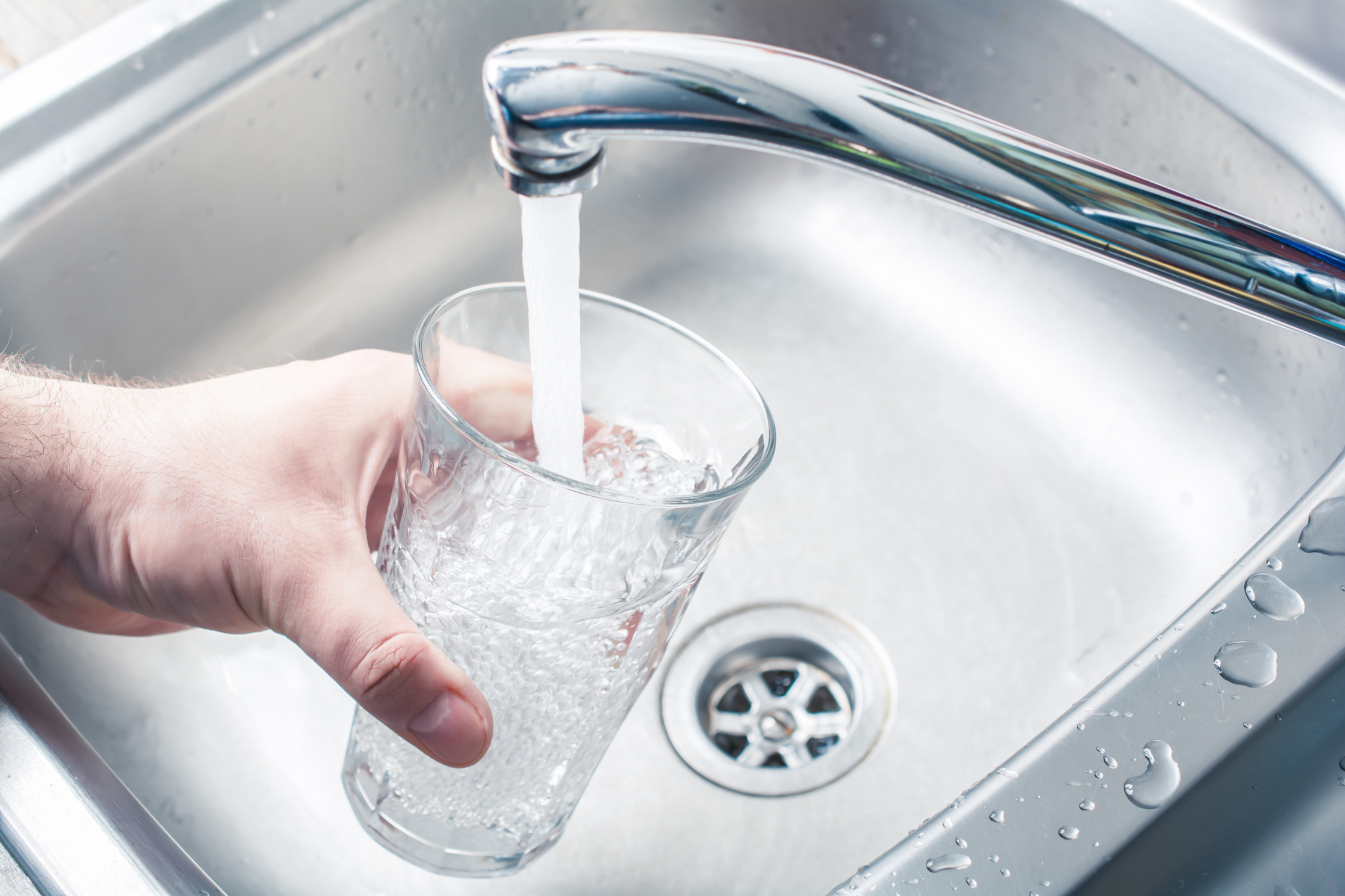A person holding a glass at a sink to get water