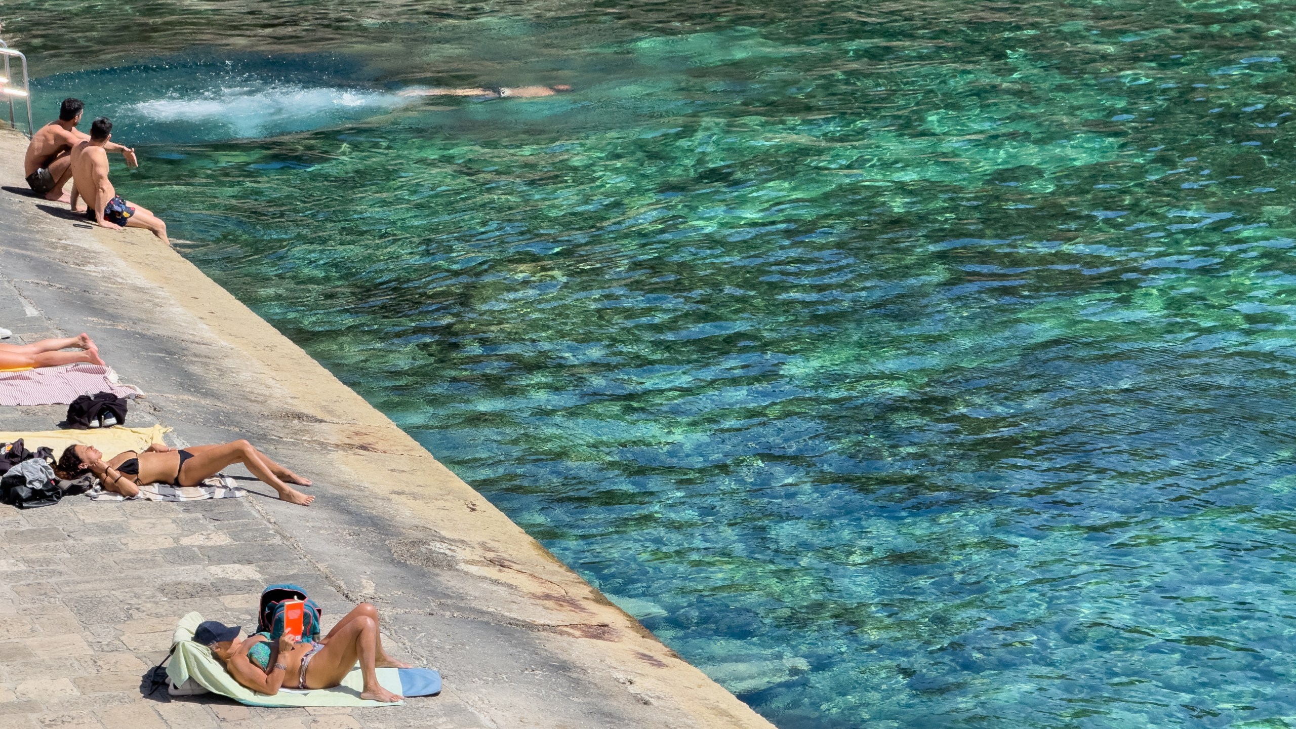 People on the beach on a warm sunny day in Tricase Porto, Italy, on March 6, 2024.