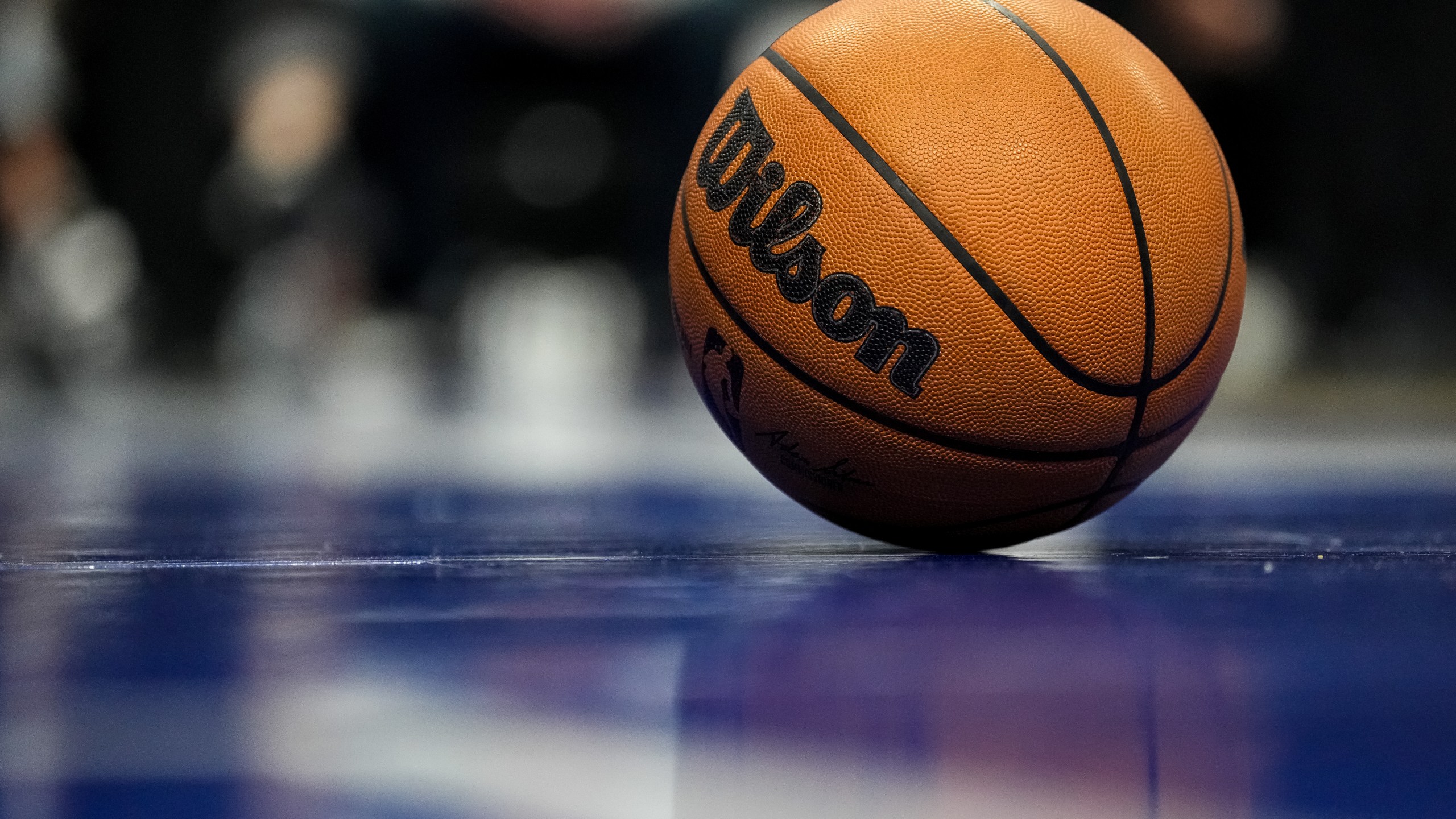 A close up of a Wilson brand official NBA game ball basketball on the court.