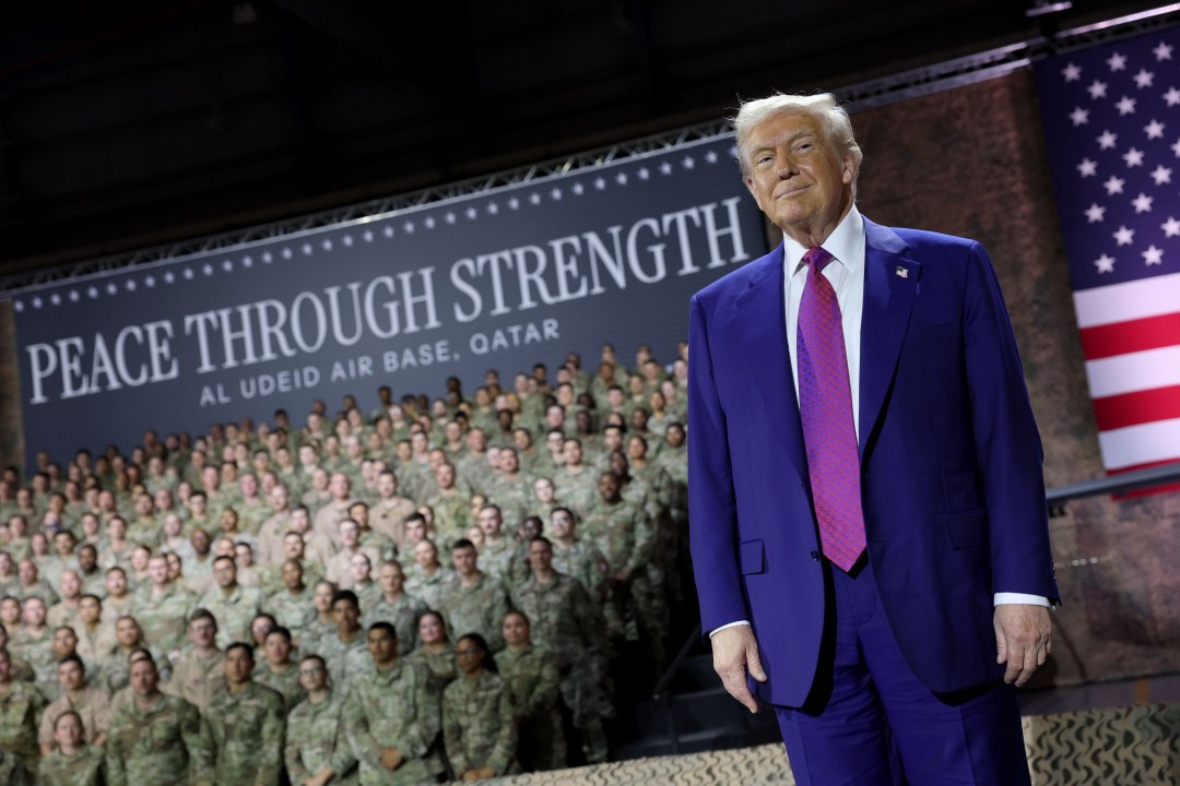 Donald J. Trump stands on stage in front of a crowd of troops