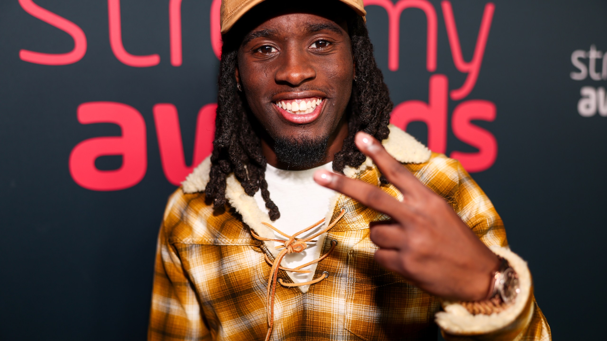 Kai Cenat gestures to the camera at an awards show