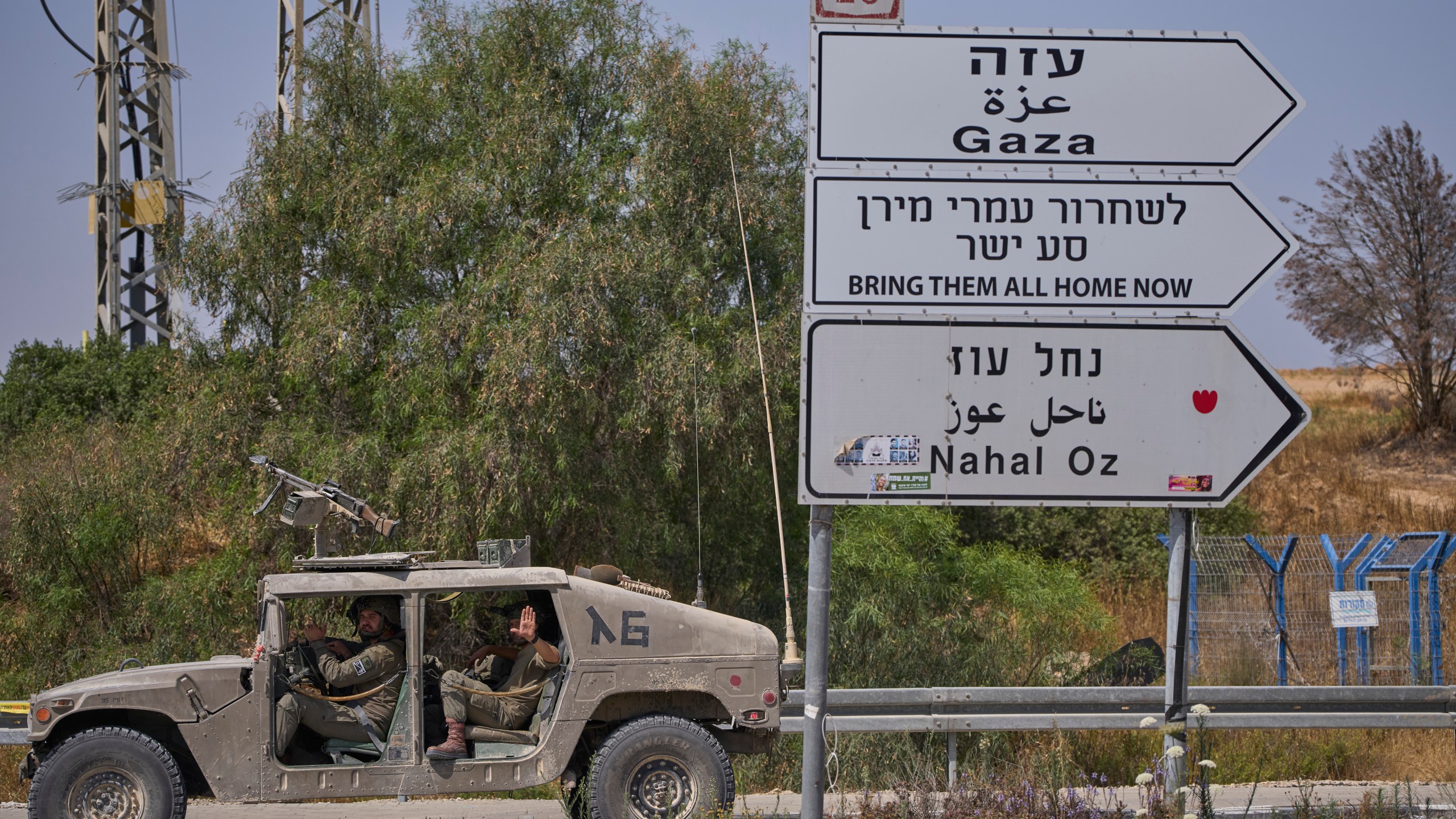 Israeli army vehicle pass by a new sign pointing towards Gaza reading "To release Omri Miron go straight" near Kibbutz Nahal Oz in southern Israel, where Miron was kidnapped from on Oct. 7, on Sunday, June 1, 2025. (AP Photo/Ohad Zwigenberg)