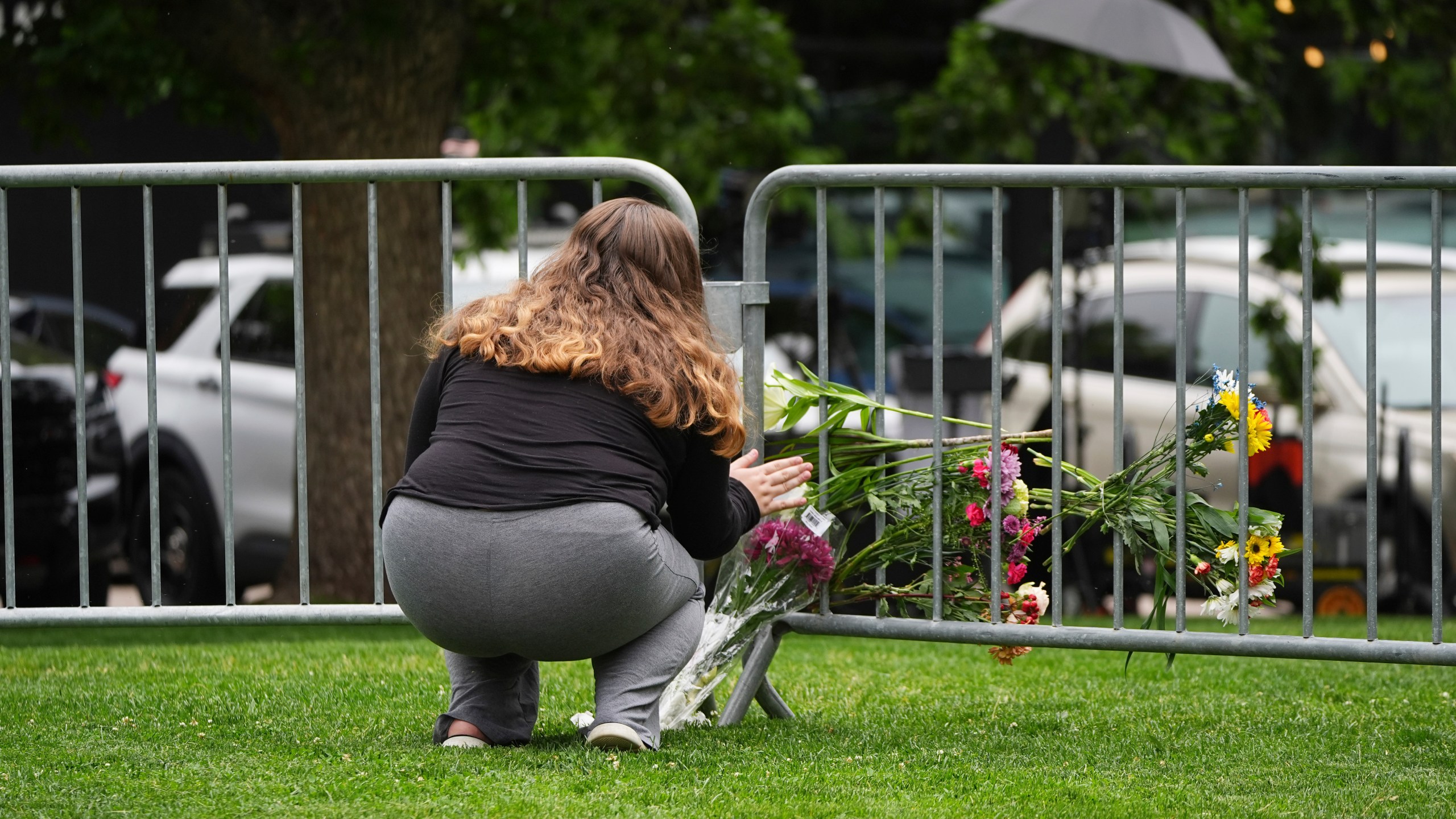 Alexandra Posnock, who moved a month ago from Skokie, Ill., to Boulder, Colo., places a bouquet of flowers along a makeshift barrier outside of the Boulder County, Colo., courthouse after Sunday's attack, Monday, June 2, 2025, in Boulder, Colo. (AP Photo/David Zalubowski)