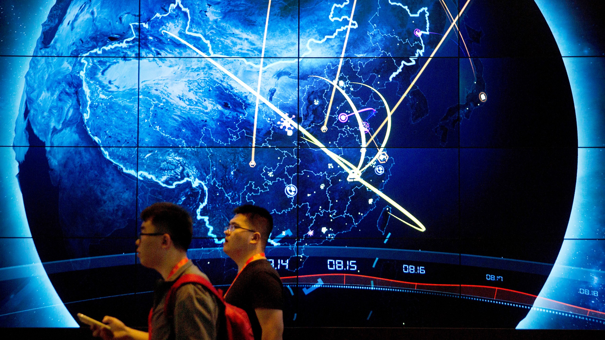 FILE - Attendees walk past an electronic display showing recent cyberattacks in China at the China Internet Security Conference in Beijing, on Sept. 12, 2017. (AP Photo/Mark Schiefelbein, File)