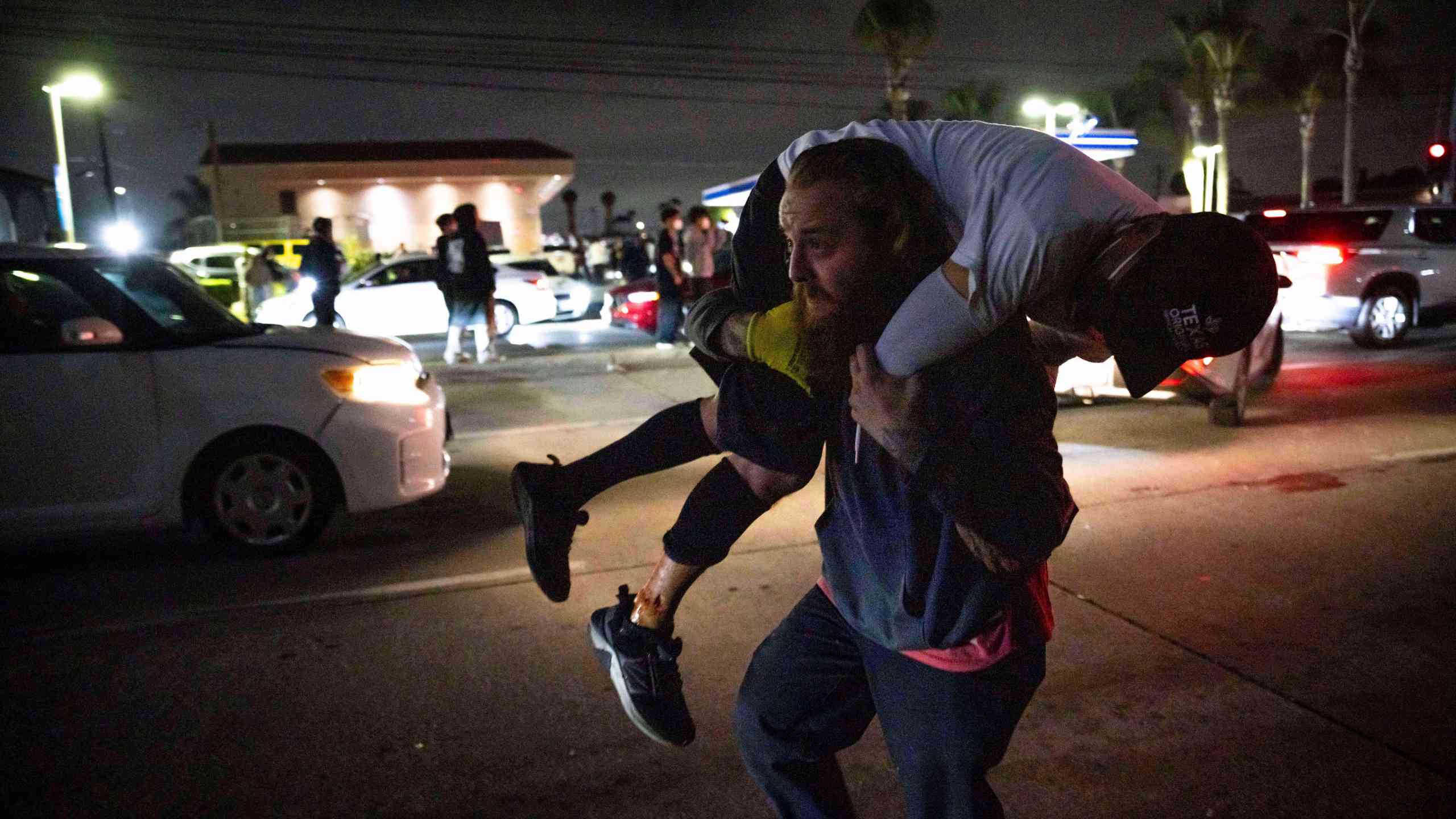 A person carries an injured protester to cover during a protest in Compton, Calif., Saturday, June 7, 2025, after federal immigration authorities conducted operations. (AP Photo/Ethan Swope)