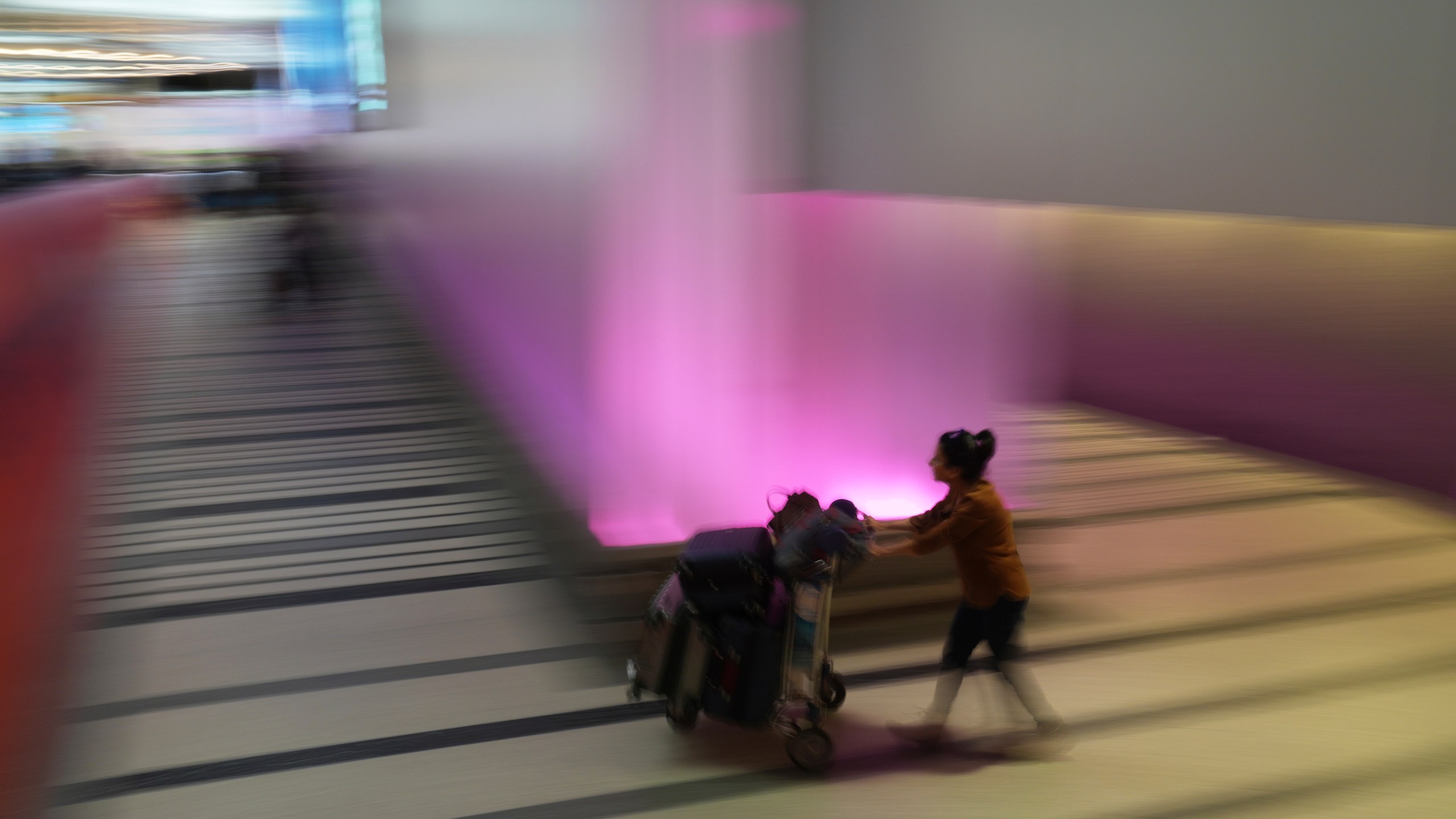 A traveler pushes a luggage cart through an airport