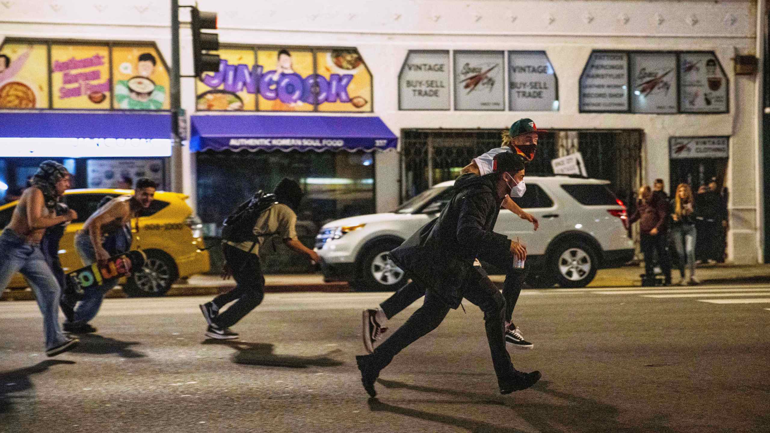 Protesters run to avoid being kettled by police during protests over the Trump administration's immigration raids in Los Angeles, Monday, June 9, 2025. (AP Photo/Ethan Swope)