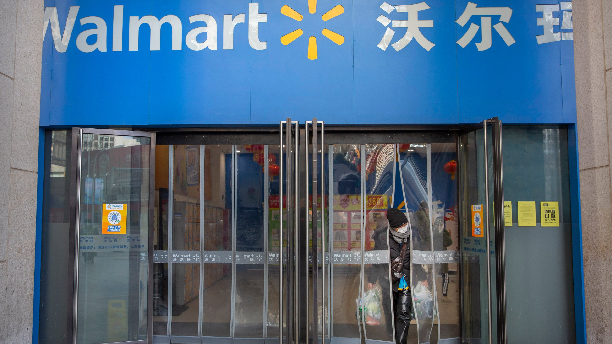 FILE - A customer wears a face mask as she leaves a Walmart grocery store in Beijing, Feb. 1, 2020. (AP Photo/Mark Schiefelbein, File)
