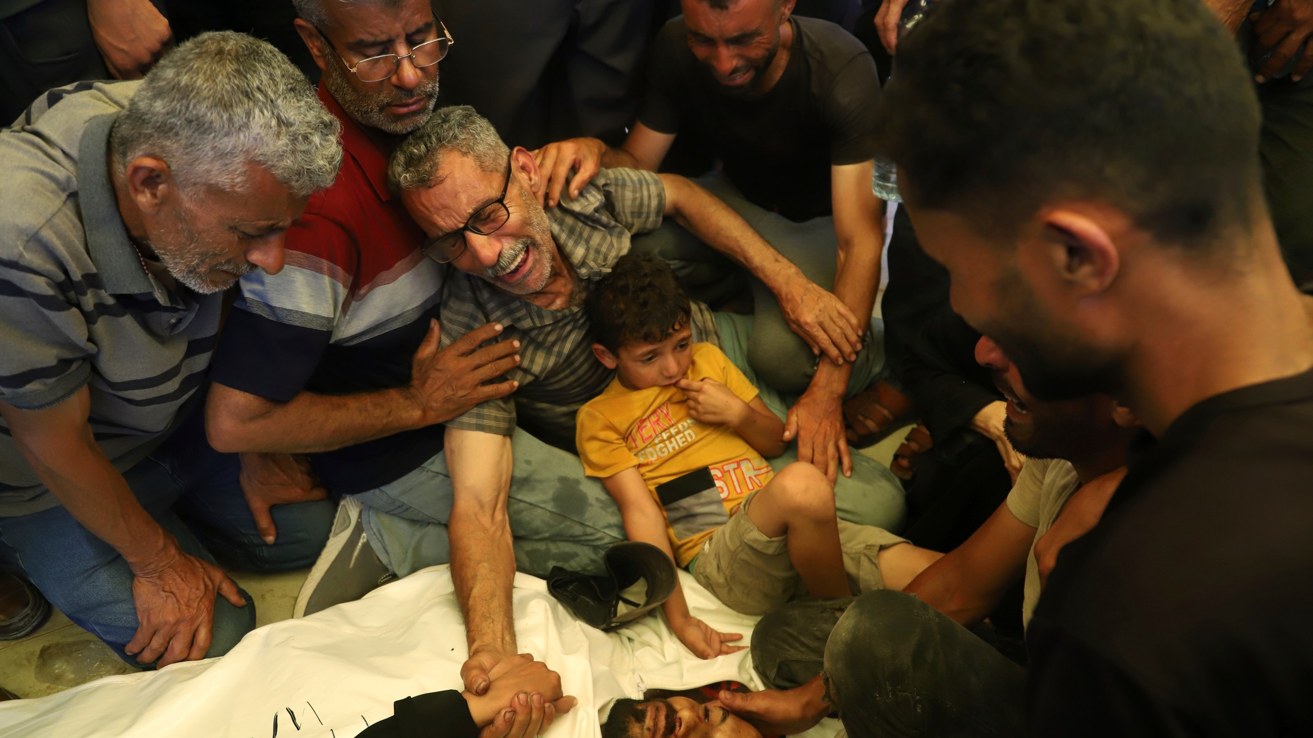 Ata Qasas, center, mourns over the body of his son Rashad Qasas, who was killed while heading to an aid distribution hub, during his funeral in Rafah, southern Gaza Strip, Wednesday, June 11, 2025. (AP Photo/Mariam Dagga)