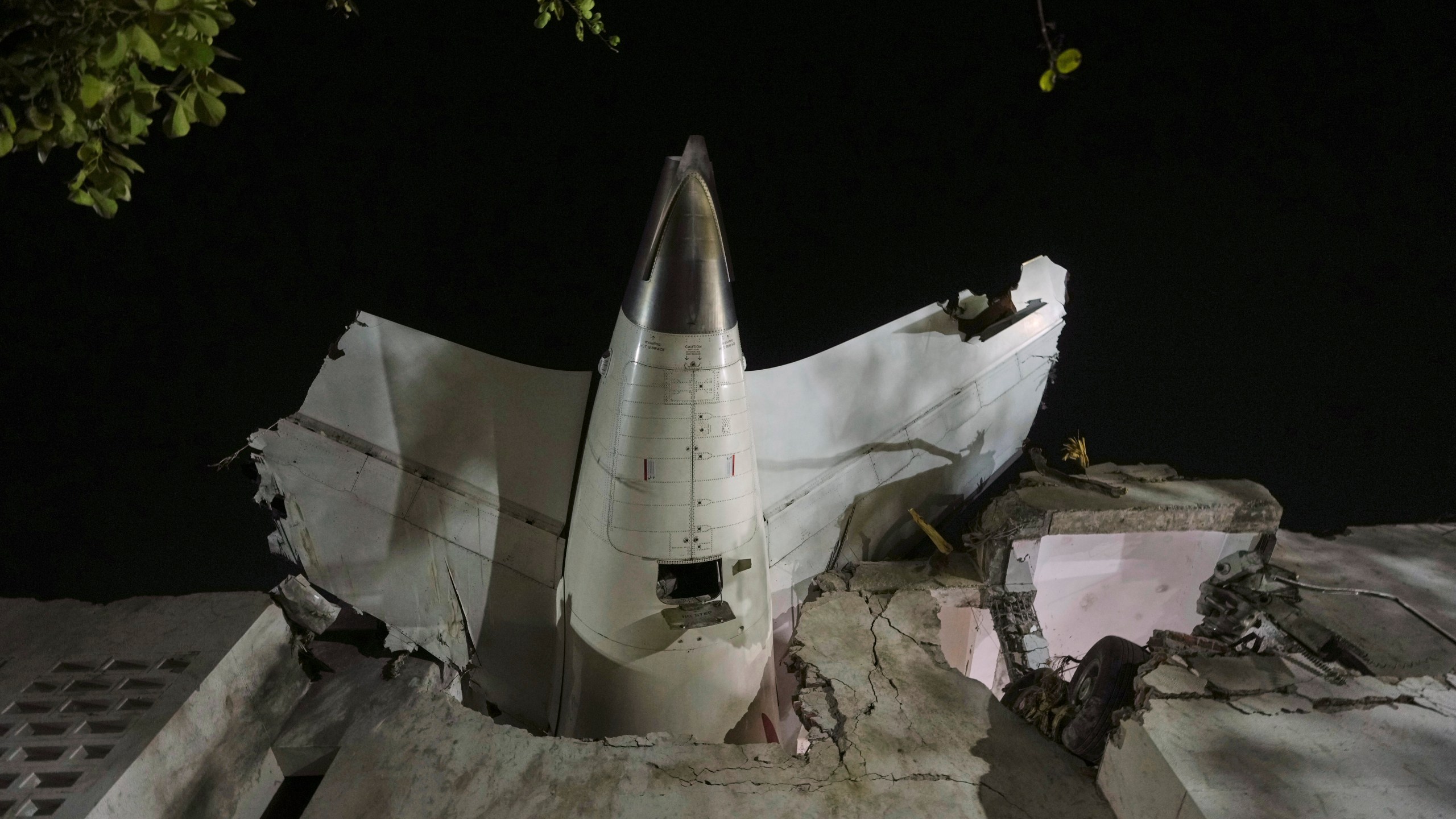 The tail of the airplane is seen stuck in a building at the site of an airplane that crashed in India's northwestern city of Ahmedabad in Gujarat state, Thursday, June 12, 2025. (AP Photo/Ajit Solanki)