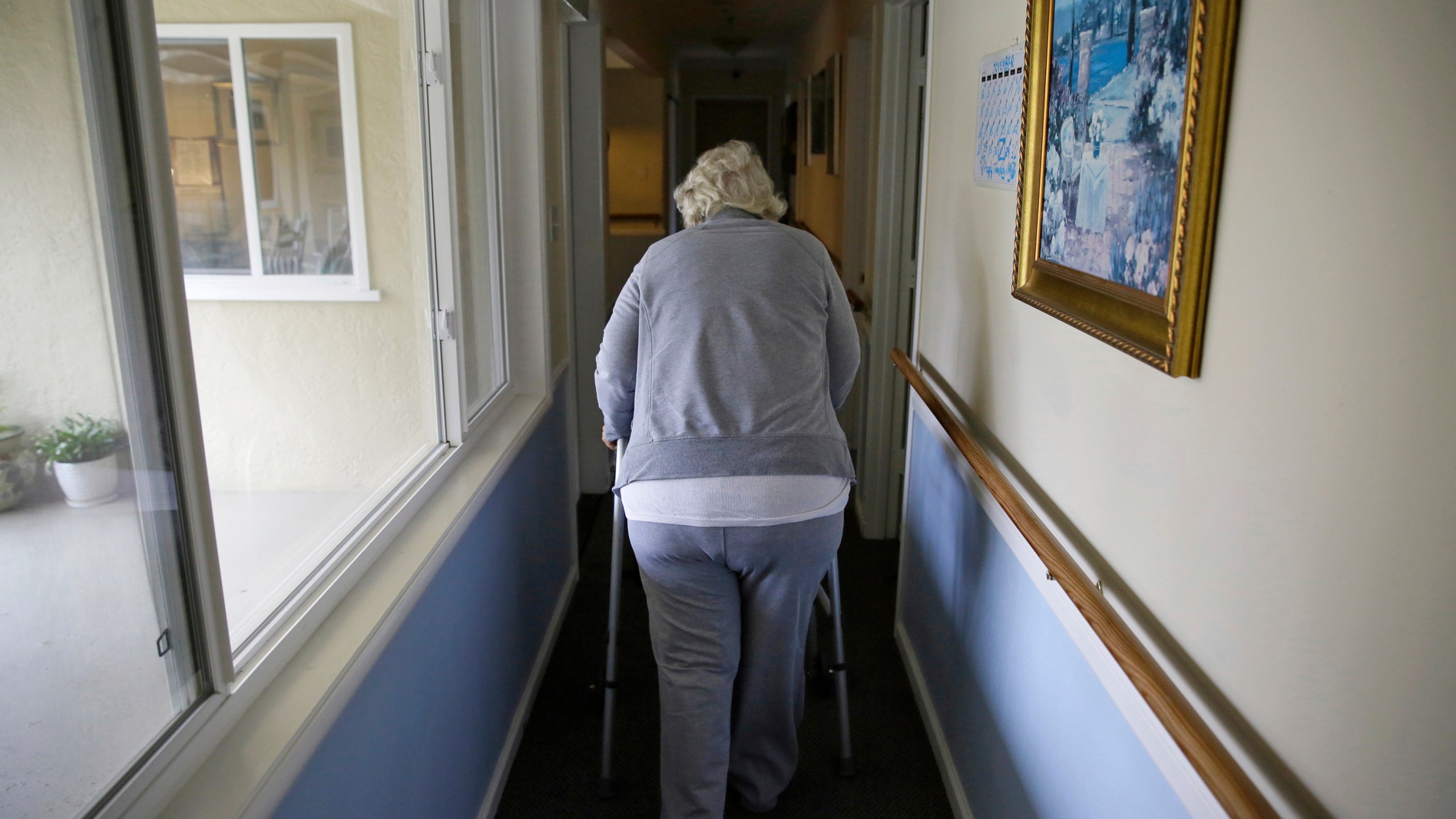FILE - A woman uses a walker as she heads to her room at a senior care home in Calistoga, Calif., on Dec. 5, 2019. (AP Photo/Eric Risberg, File)