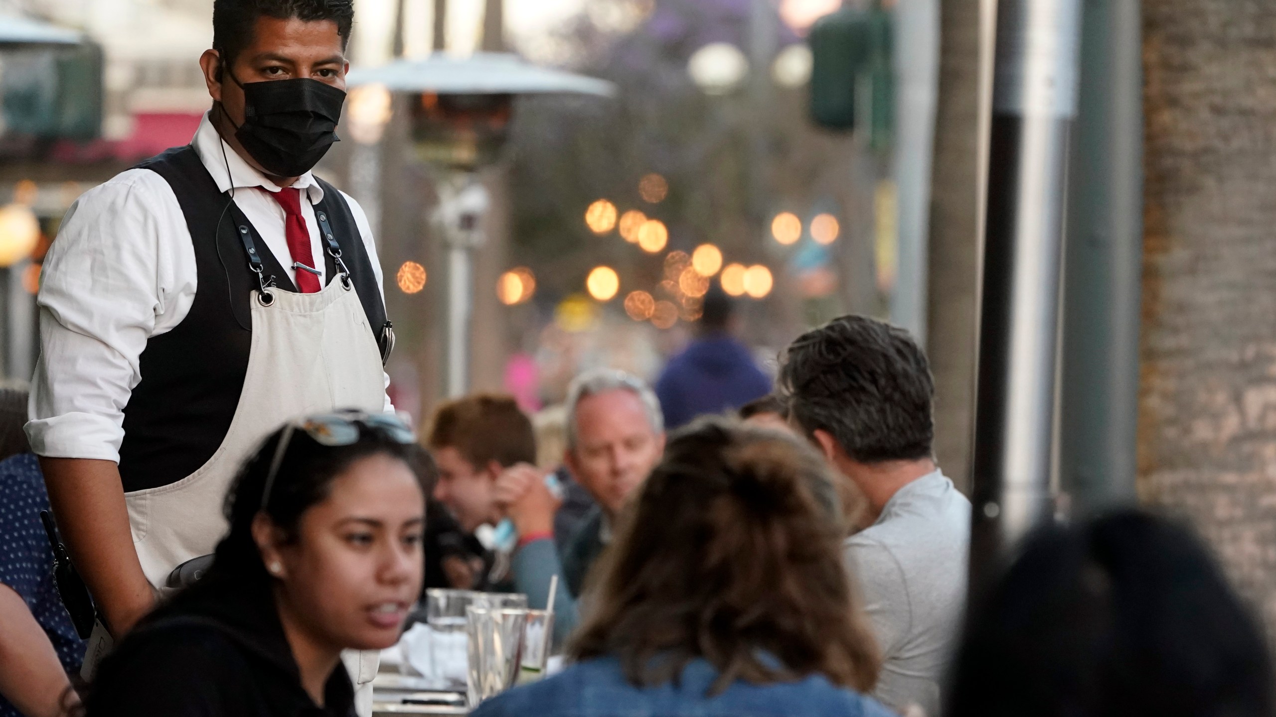FILE - A server tends to customers in an outdoor dining area on The Promenade in Santa Monica, Calif., June 9, 2021. (AP Photo/Marcio Jose Sanchez, File)