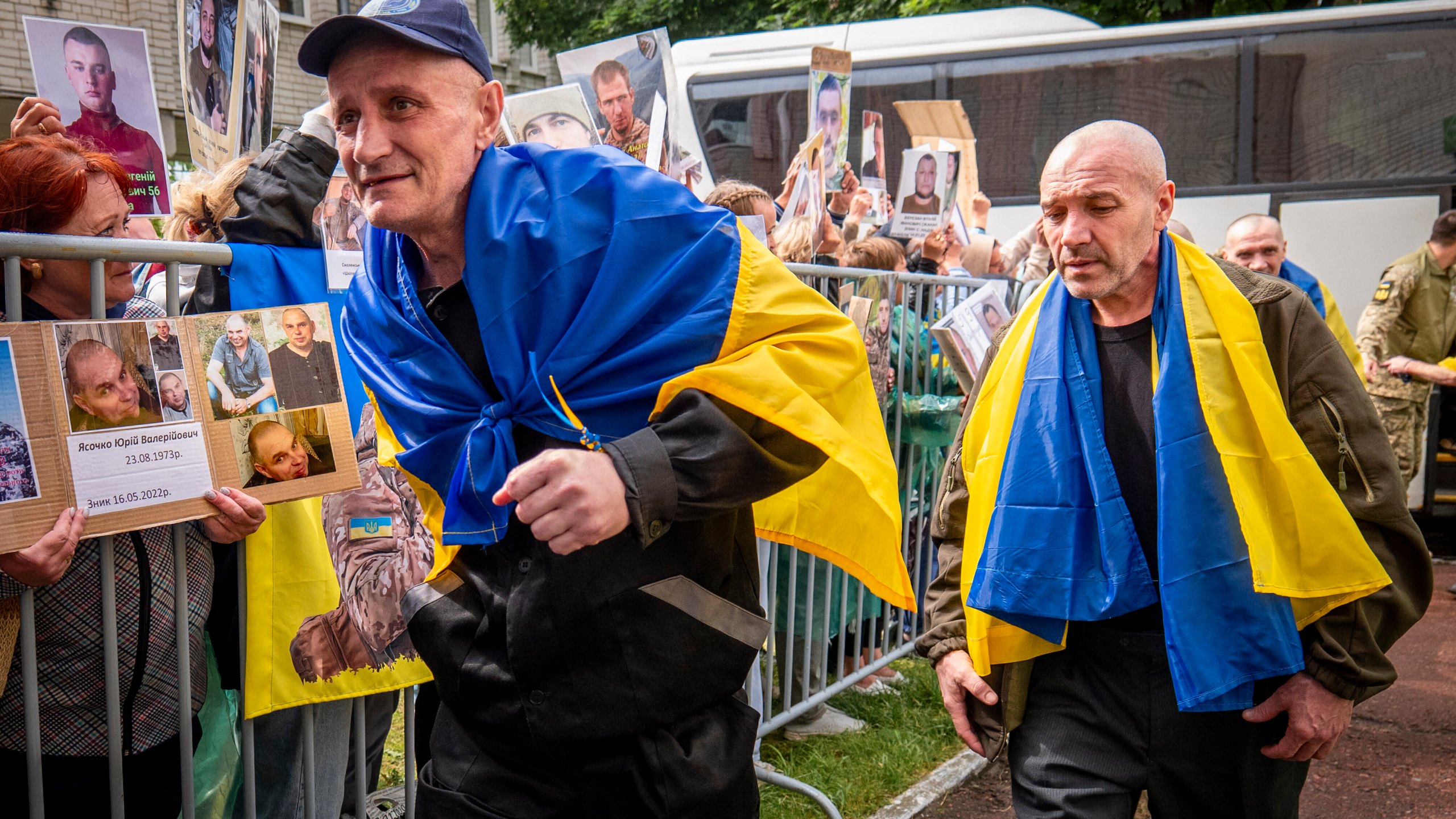 Freed Ukrainian soldiers arriving after a POW exchange with Russia walk past Ukrainians holding photos of their missing relatives in the Chernyhiv region, Ukraine, Friday, June 20, 2025. (AP Photo/Dan Bashakov)