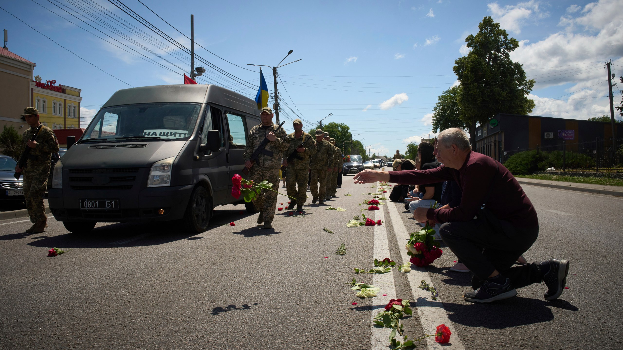 Villagers throw flowers on the road during a funeral procession