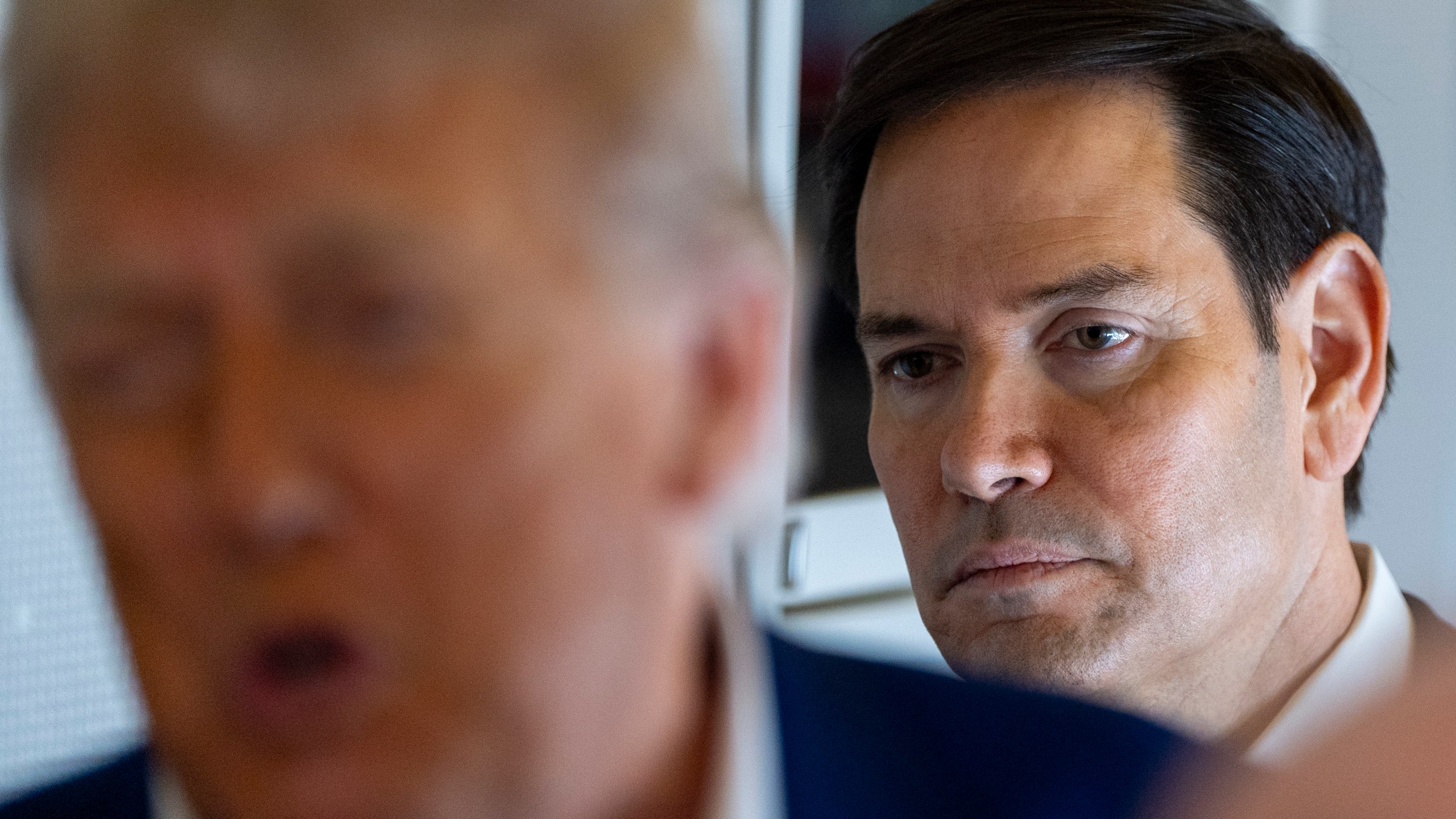 Secretary of State Marco Rubio stands behind as President Donald Trump speaks with reporters on Air Force One while in flight from Joint Base Andrews, Md., to Amsterdam, Netherlands, Tuesday, June 24, 2025. (AP Photo/Alex Brandon)