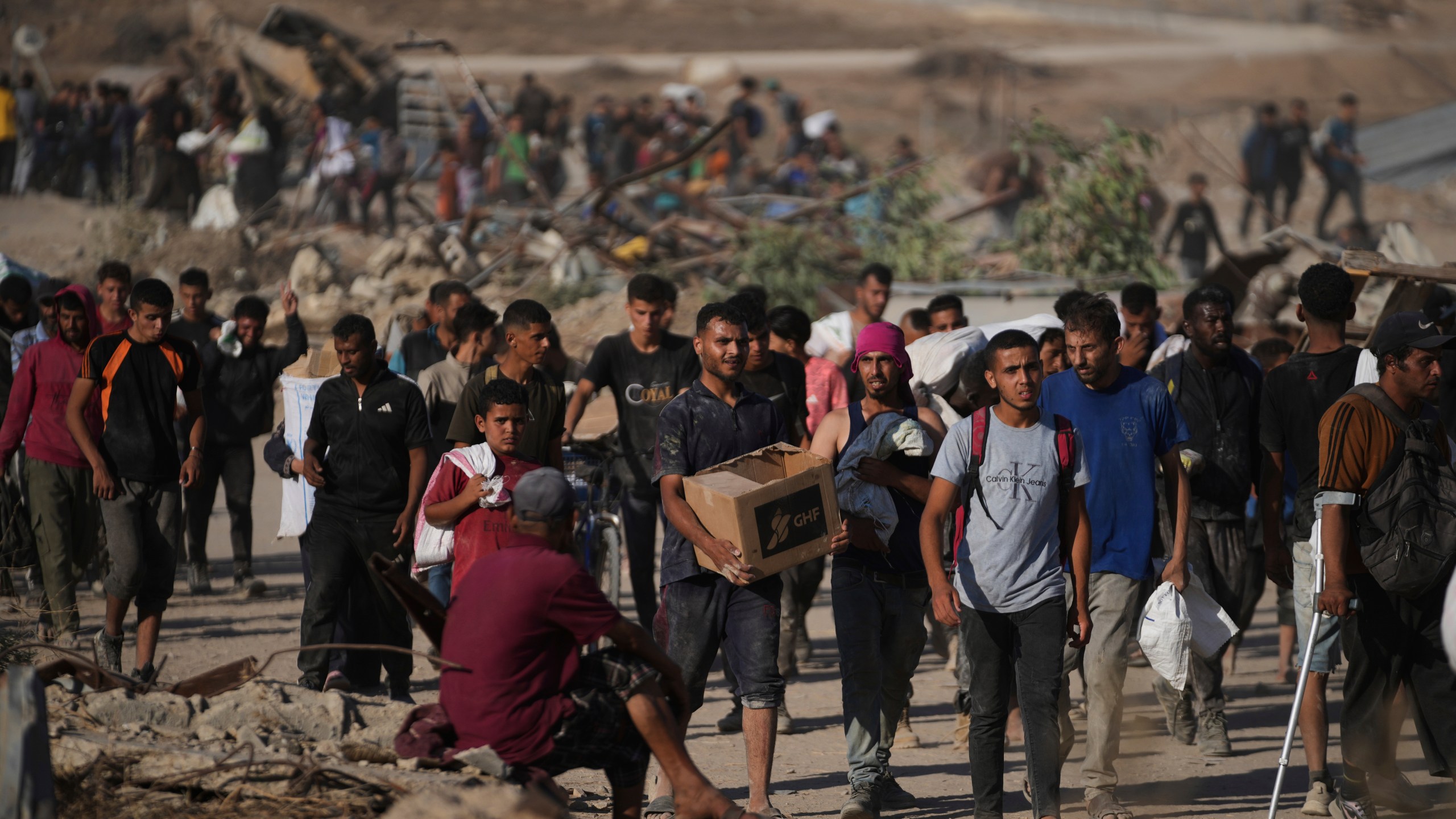Palestinians carry humanitarian aid packages near the Gaza Humanitarian Foundation distribution center operated by the U.S.-backed organization in Khan Younis, southern Gaza Strip, Thursday, June 26, 2025. (AP Photo/Abdel Kareem Hana)