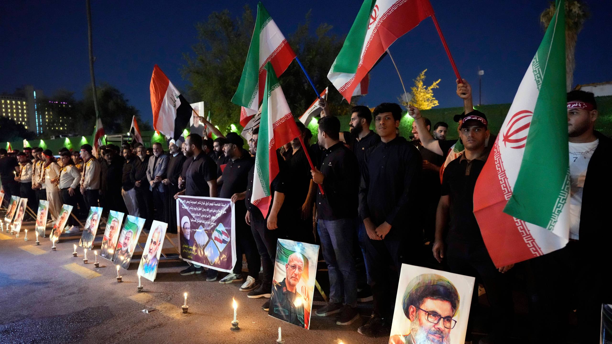 Protesters gather in front of the Iranian embassy carrying candles and Iranian flags during a stand honoring the Iranian armed forces generals, nuclear scientists, and their family members who were killed in Israeli strikes, in Baghdad, Iraq, Saturday, June 28, 2025. (AP Photo/Hadi Mizban)