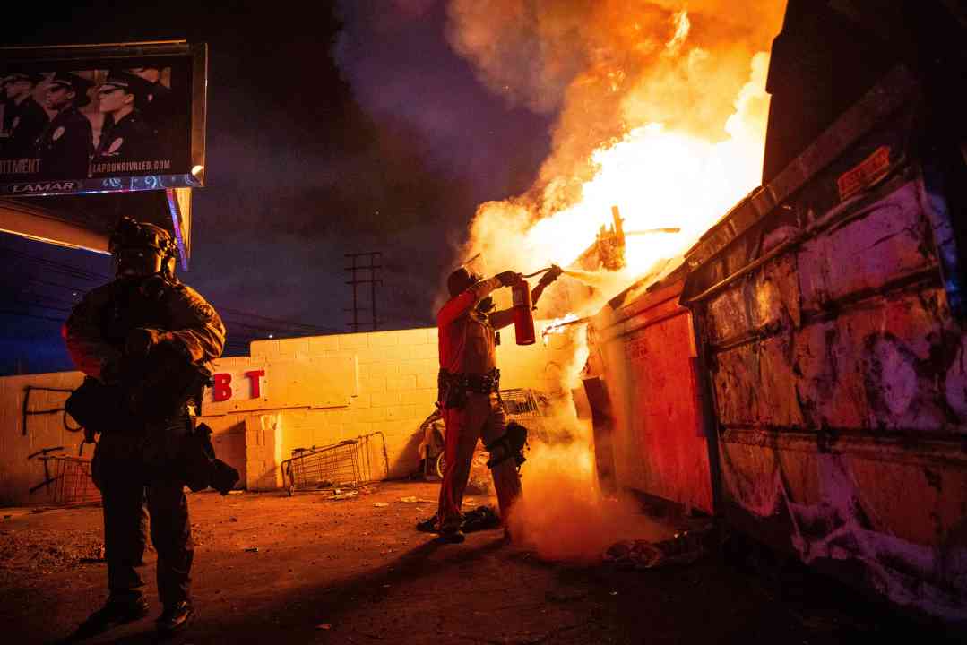 A law enforcement officer works to put out a fire during a protest in Compton, Calif., Saturday, June 7, 2025, after federal immigration authorities conducted operations.