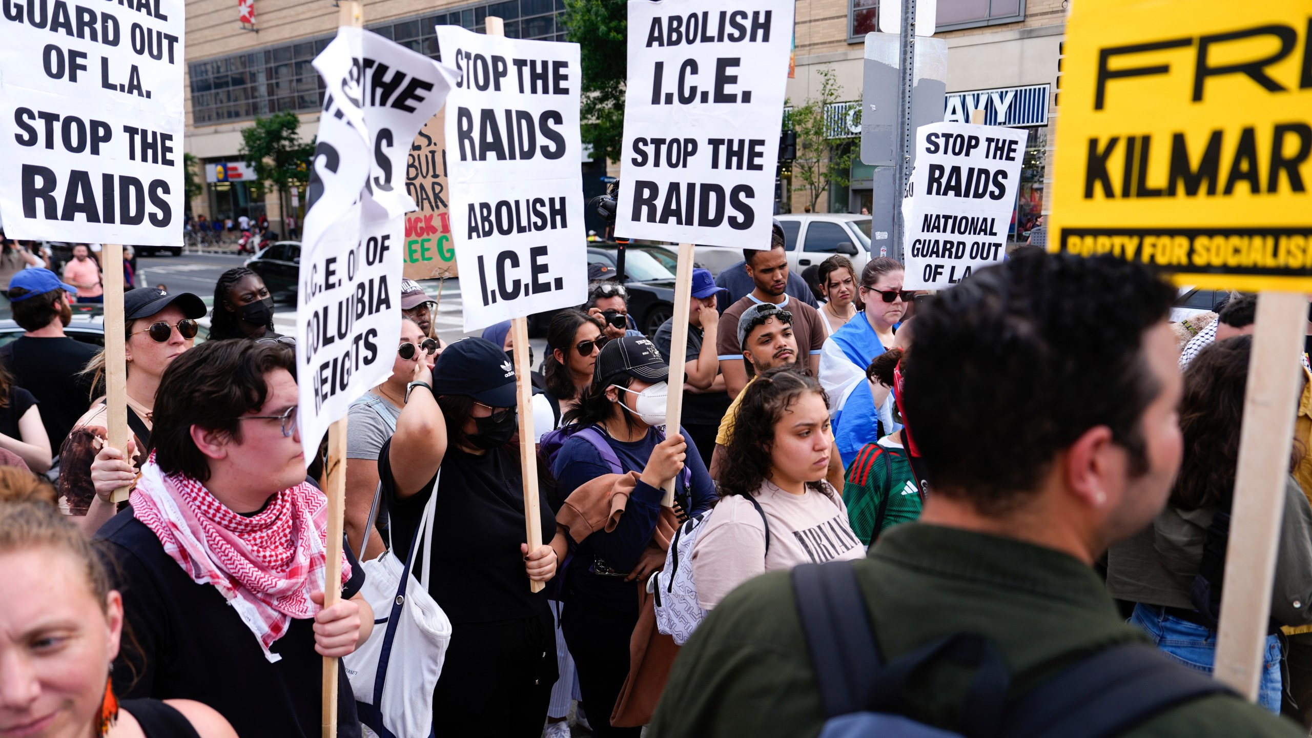 Demonstrators hold signs during protest against ICE raids