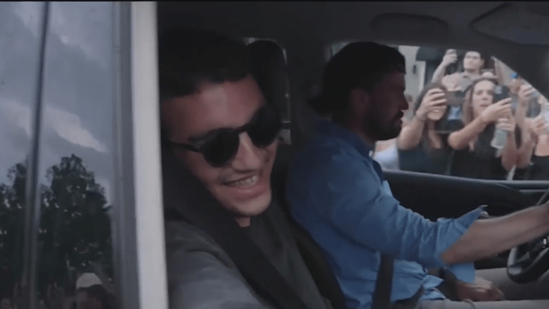 Edan Alexander smiles in the passenger seat of a car