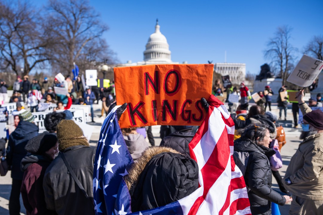 hands holding a 'NO KINGS' sign in Washington