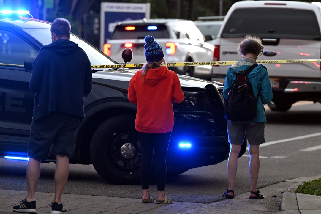 police officers work the scene while onlookers wait