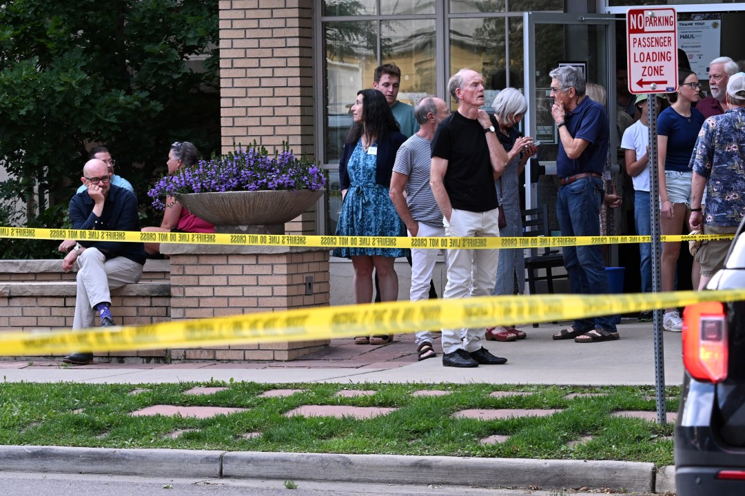 People wait behind police tape to be allowed back into areas cordoned off by law enforcement 