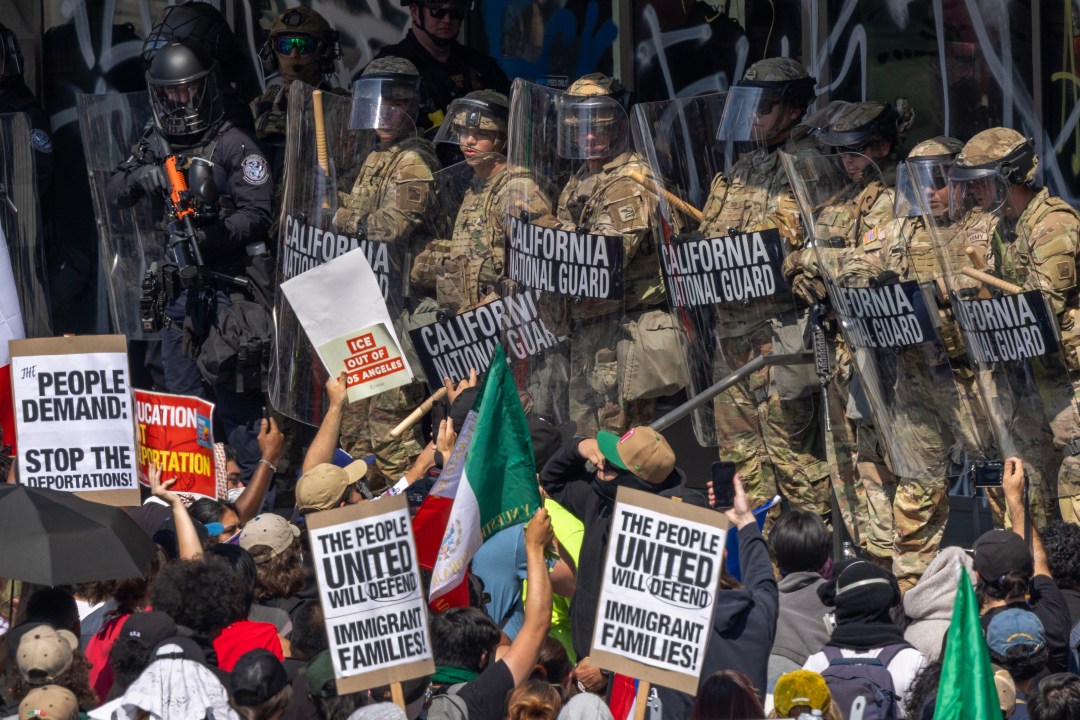 A police officer holds a rifle surrounded by protesters