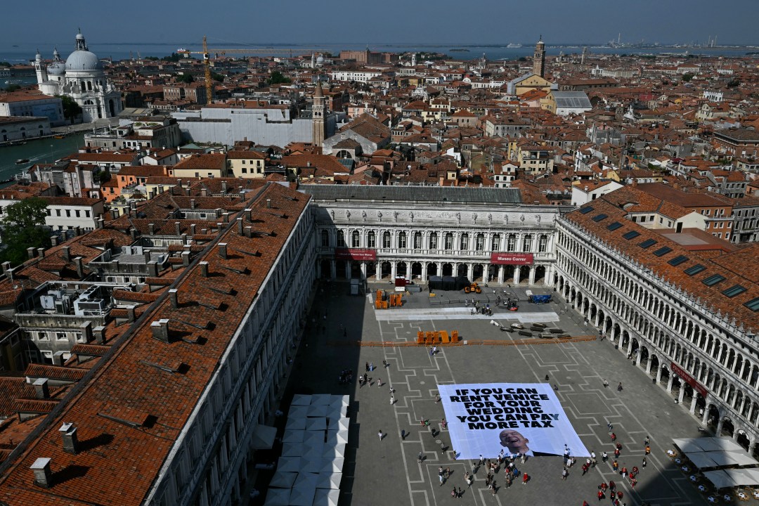 Top view of "If you can rent Venice for your wedding you can pay more tax" sign with Bezos face on it
