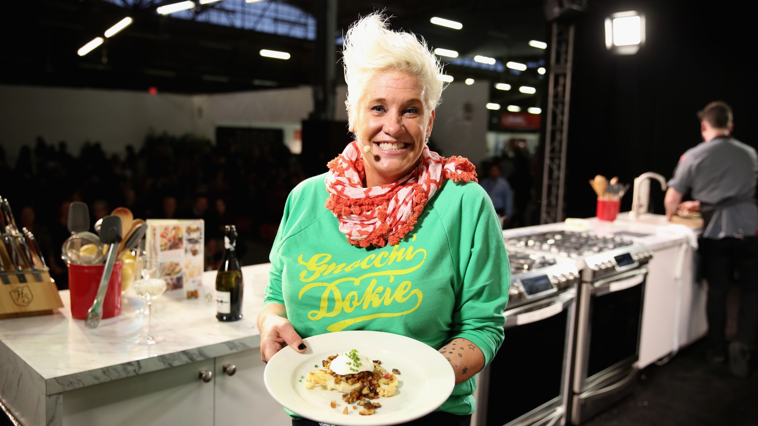 Chef Anne Burrell smiling while holding a dish
