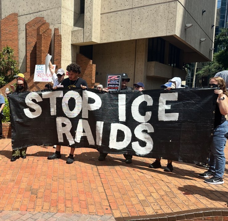 protesters holding a banner reading STOP ICE RAIDS