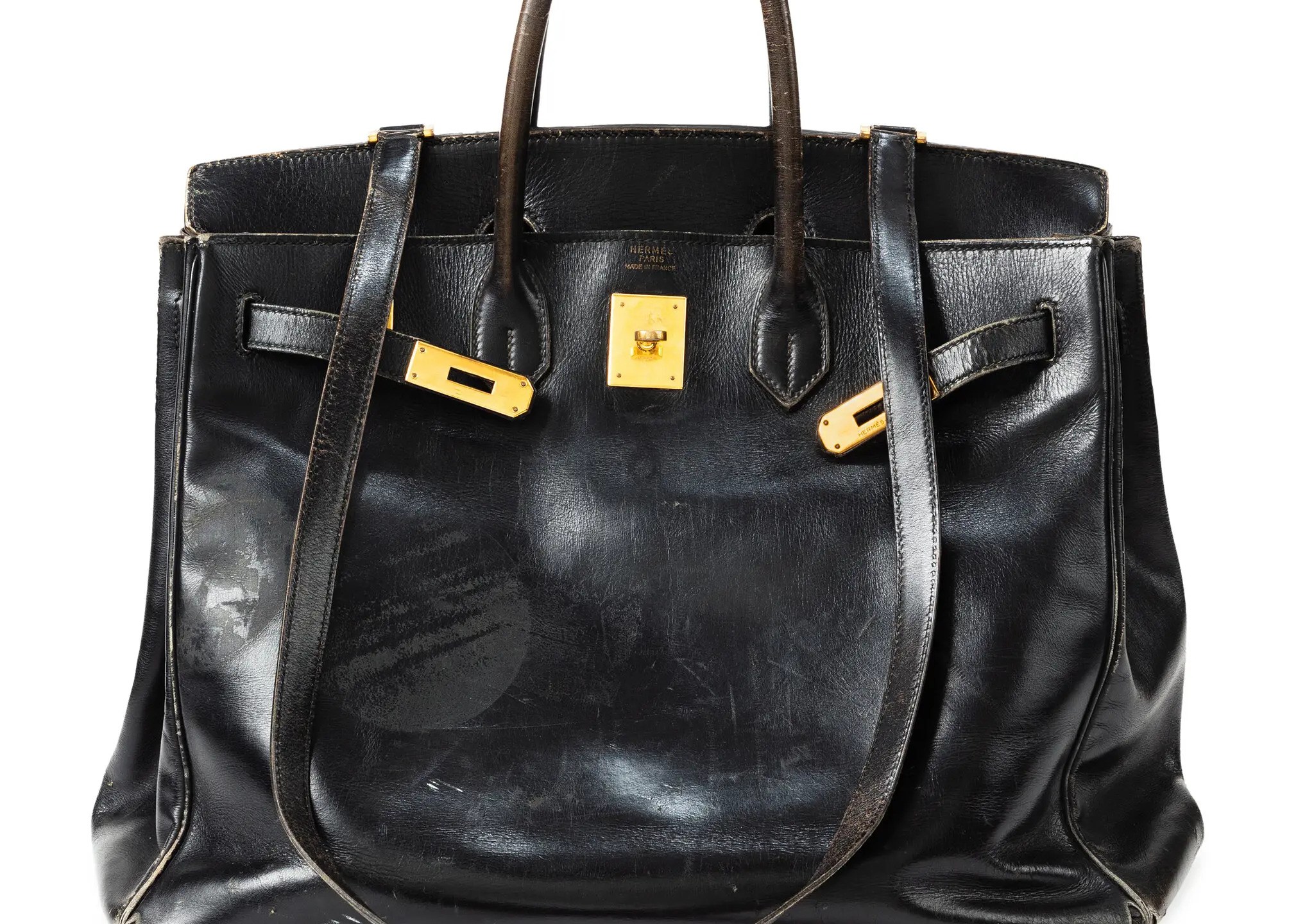 A black handbag with brass hardware in front of a white background